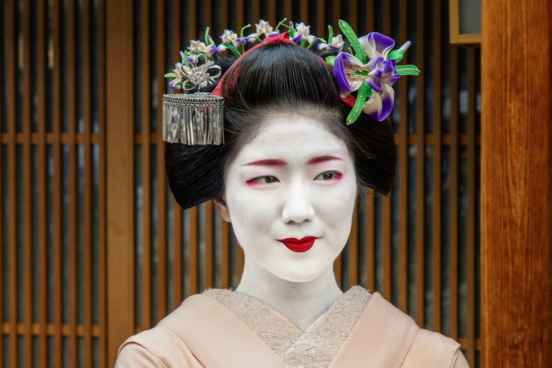 Portrait of a geisha in traditional attire with floral hairpiece in Kyoto, Japan.