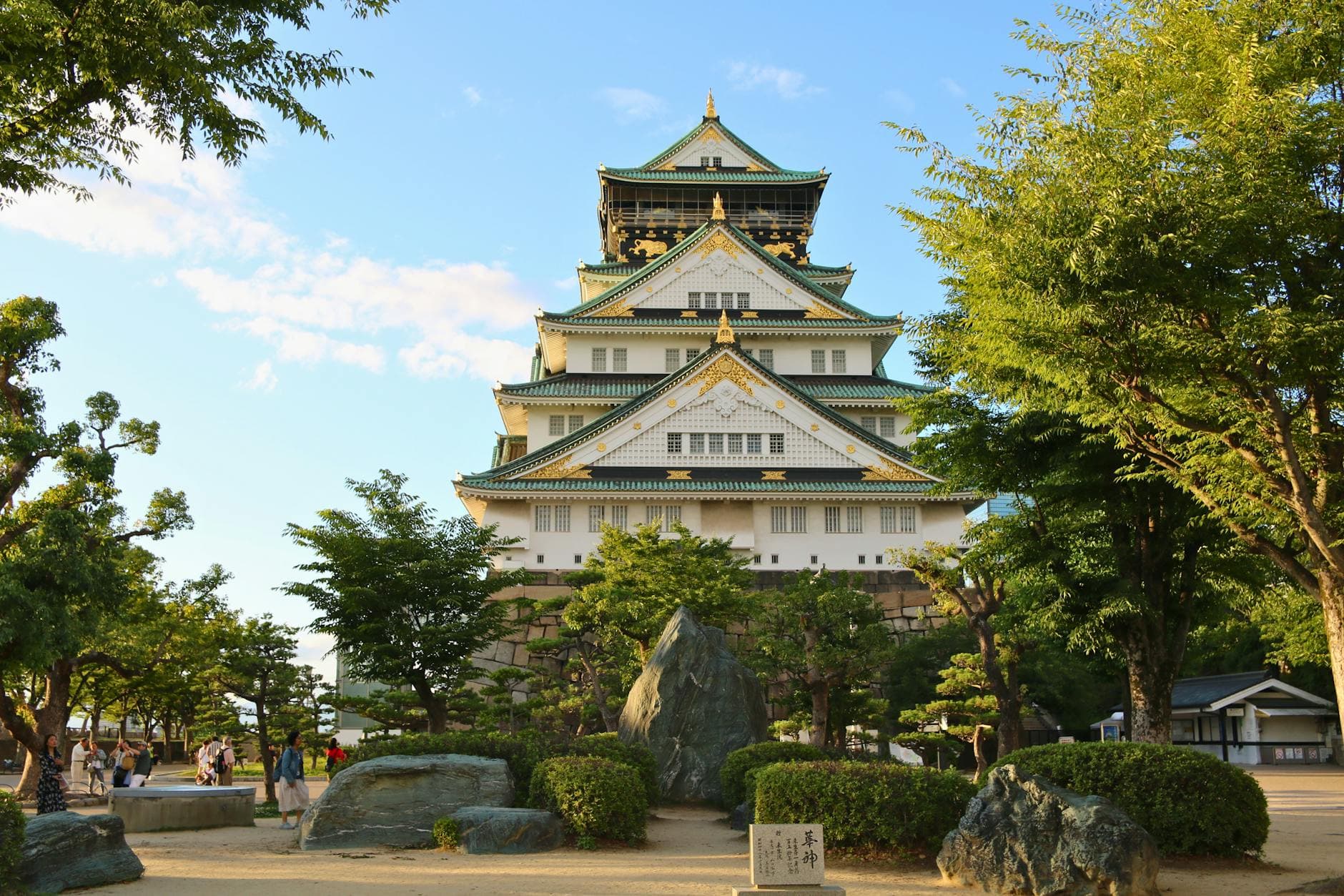 Captivating image of Osaka Castle surrounded by lush greenery under a clear blue sky.
