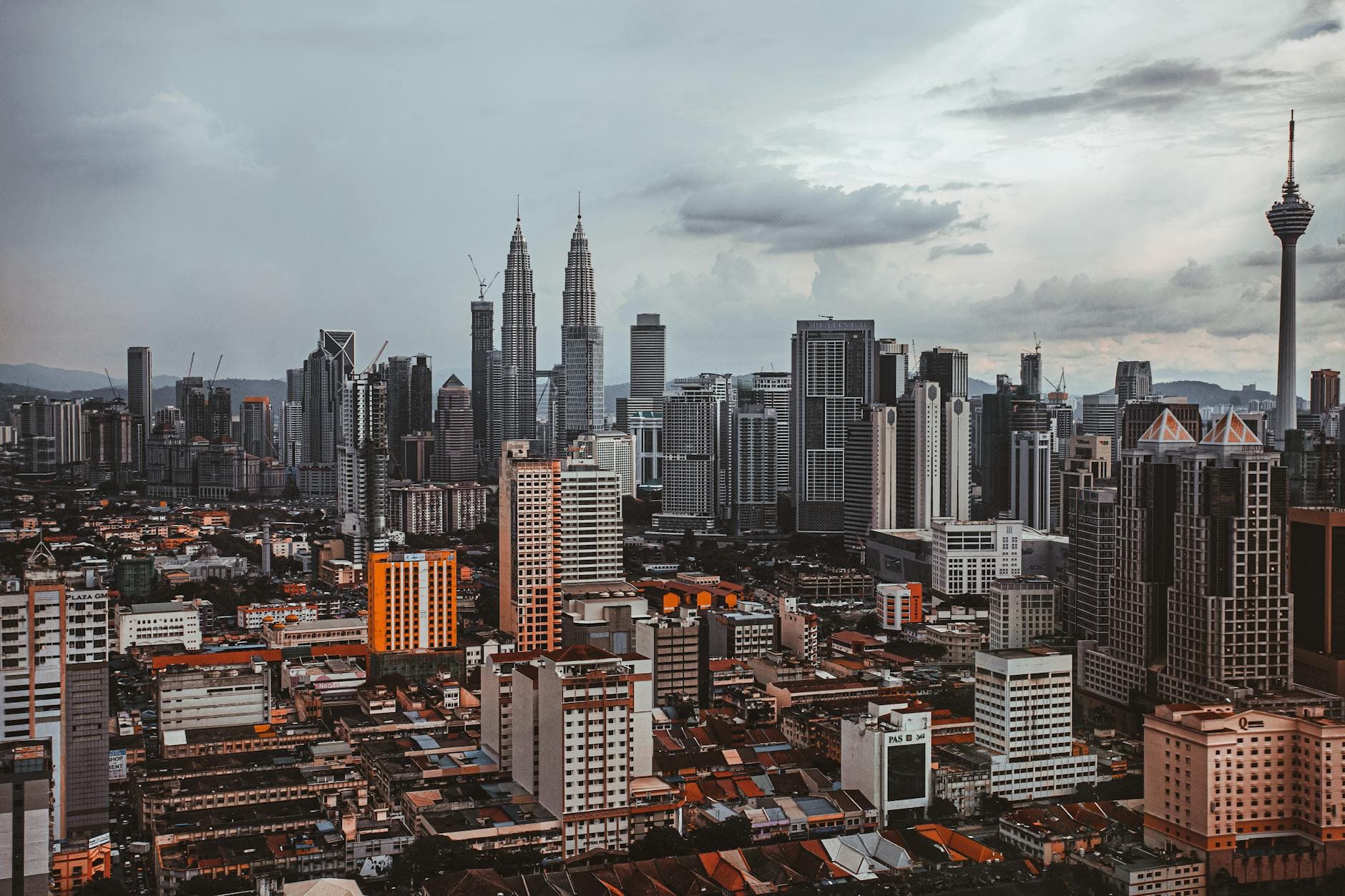 Aerial cityscape of Kuala Lumpur featuring the Petronas Twin Towers and Kuala Lumpur Tower.