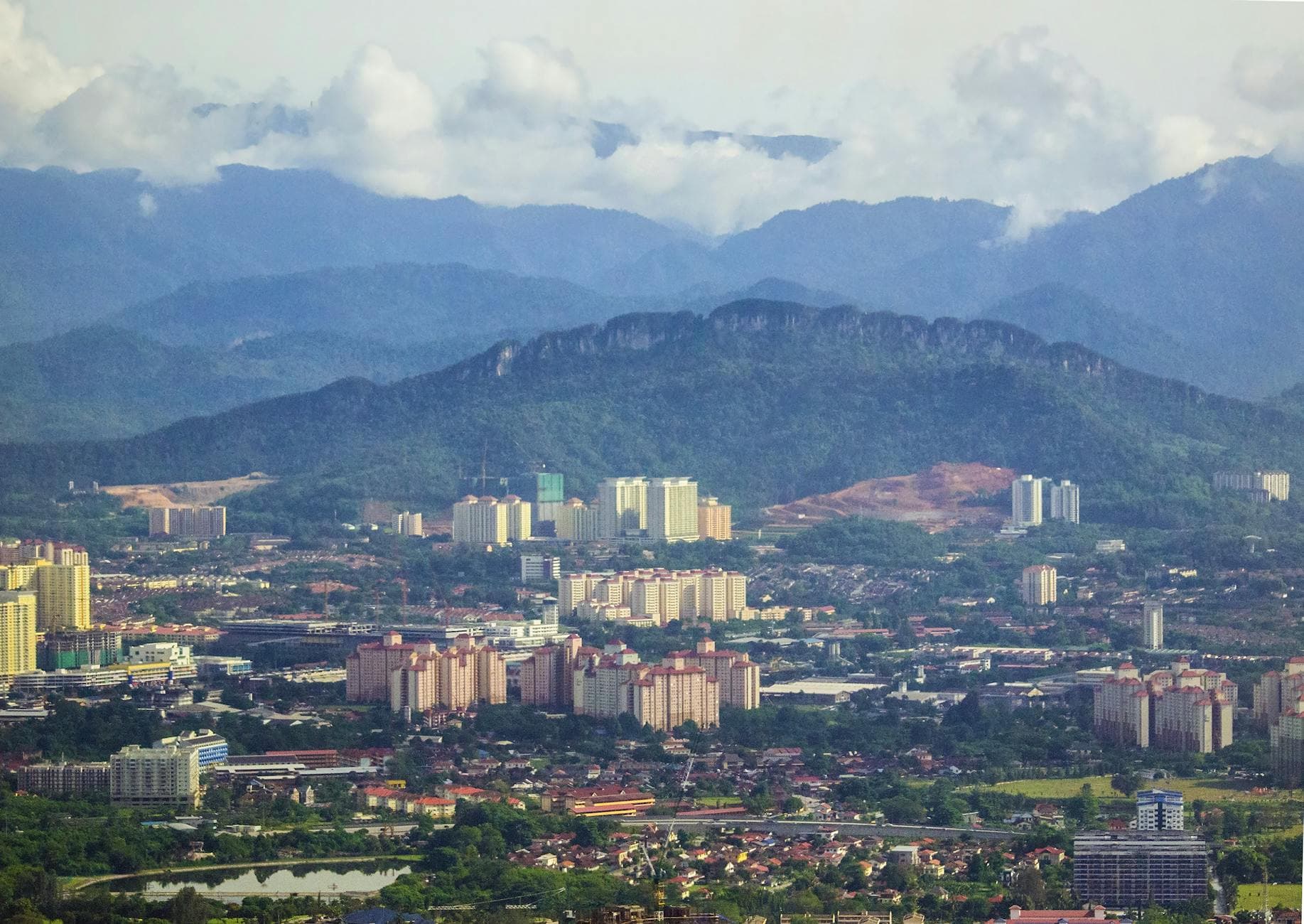 Stunning aerial shot of urban landscape with mountain backdrop under a cloudy sky.