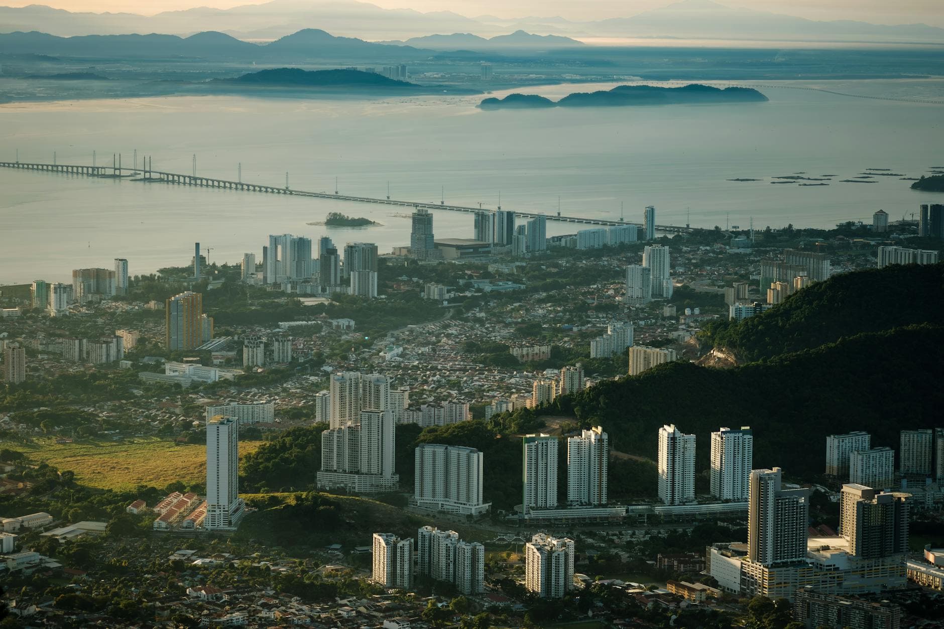 Stunning aerial view of Penang's skyline with the iconic Penang Bridge at sunrise.