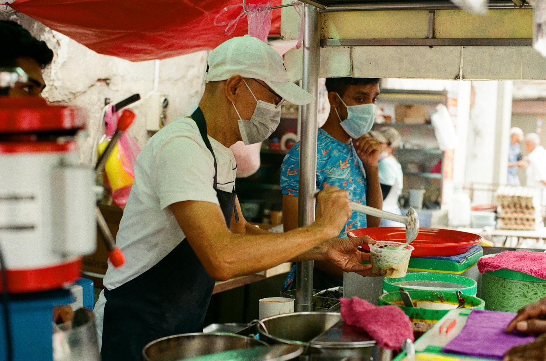 Authentic street food vendor serving customers at a bustling market in Penang, Malaysia.