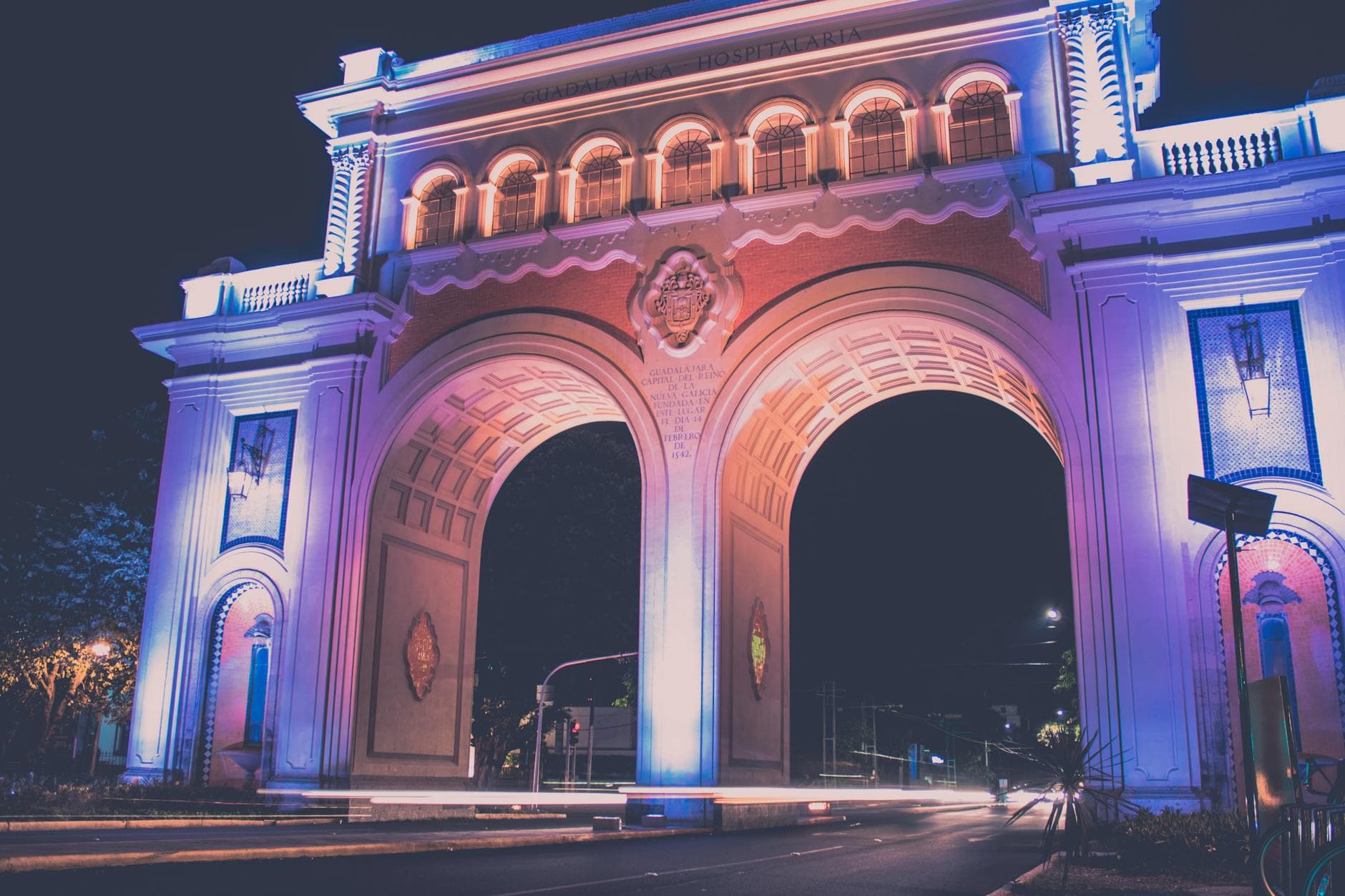 Beautiful nighttime view of an illuminated arch in Guadalajara, showcasing vibrant lighting and urban scenery.