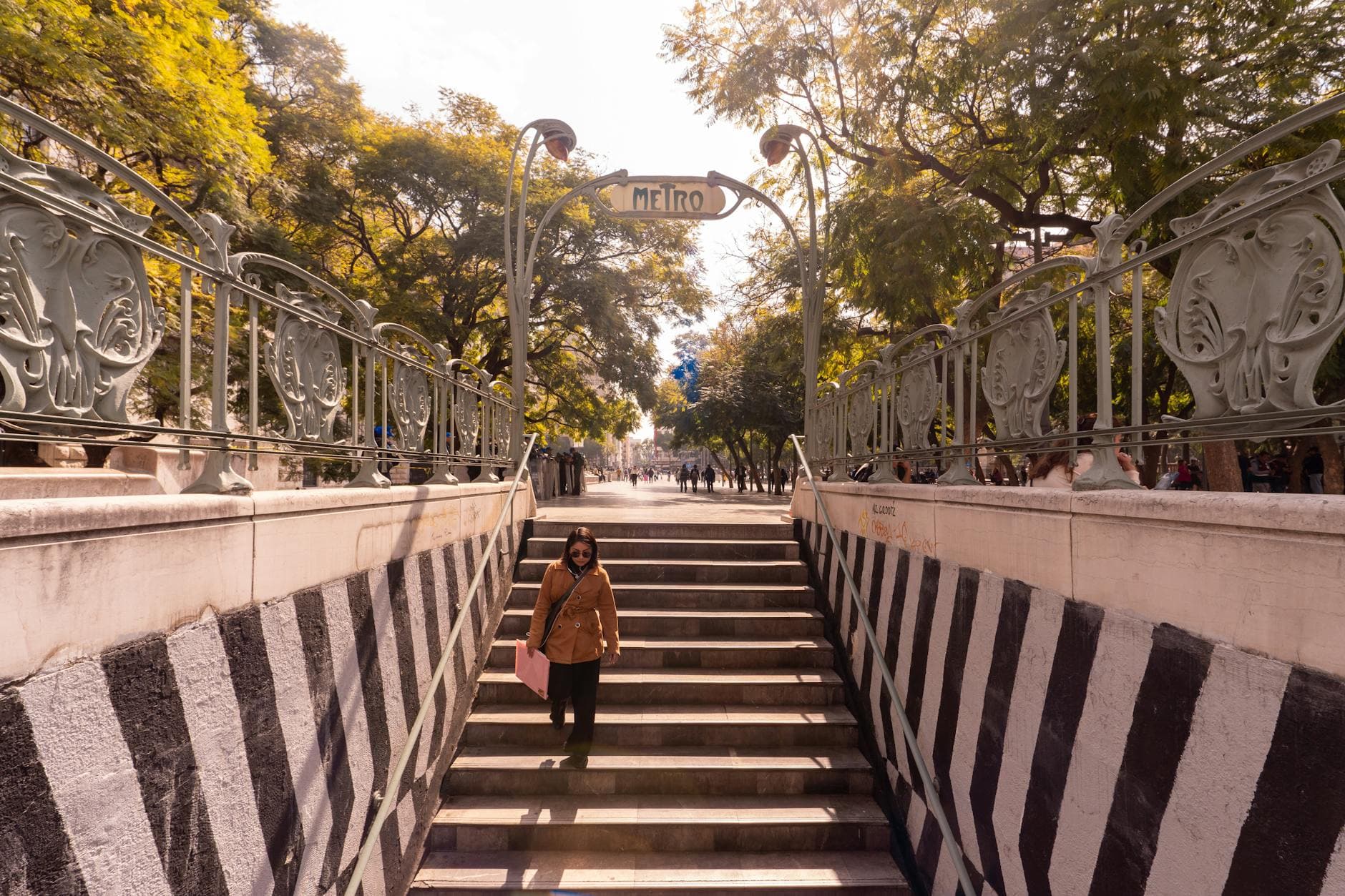 An artistic metro entrance with ornate design in a busy street of Mexico City.