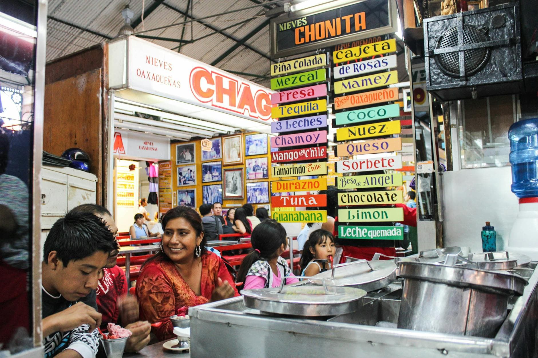 A lively Mexican ice cream shop with colorful signs and diverse customers enjoying treats.