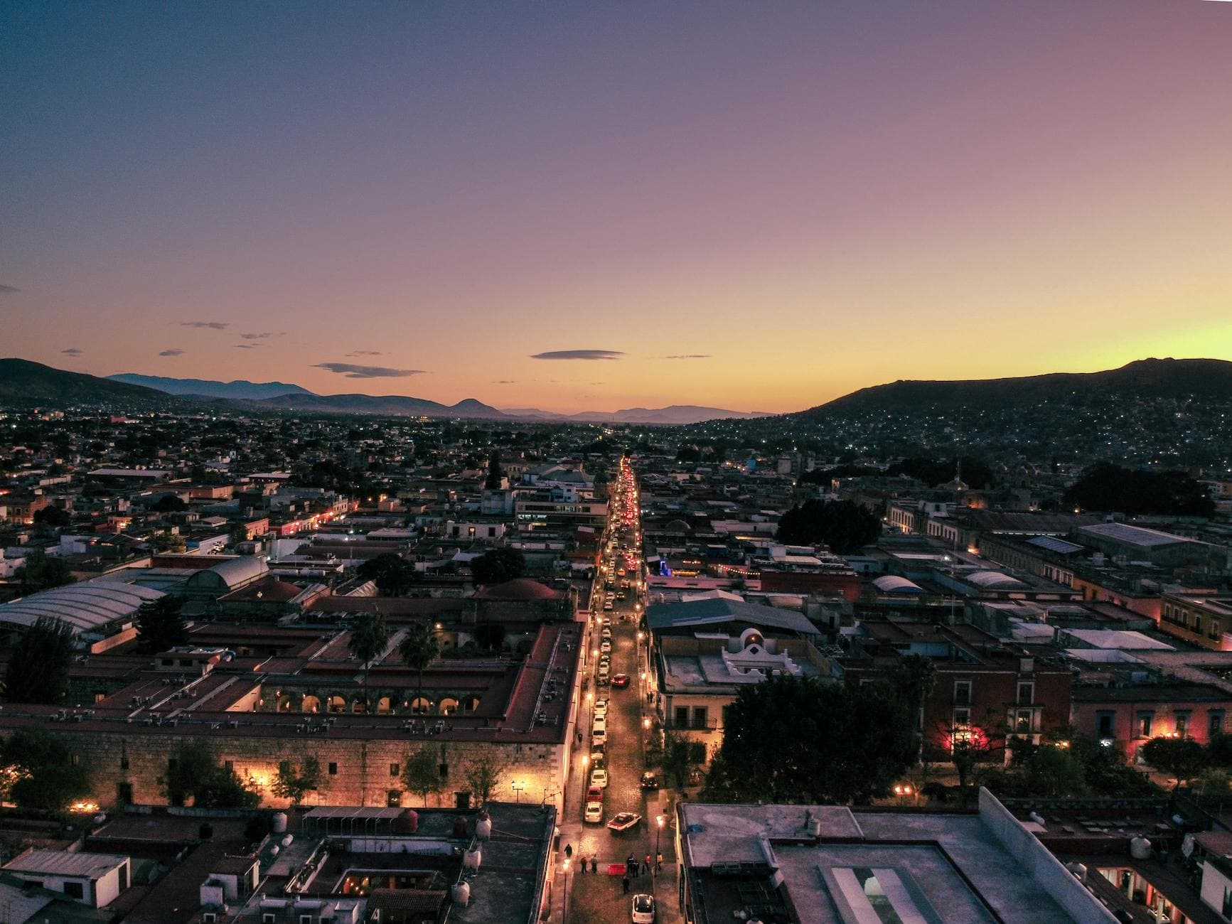 Captivating aerial view of Oaxaca de Juárez at sunset showcasing vibrant city lights and scenic landscape.