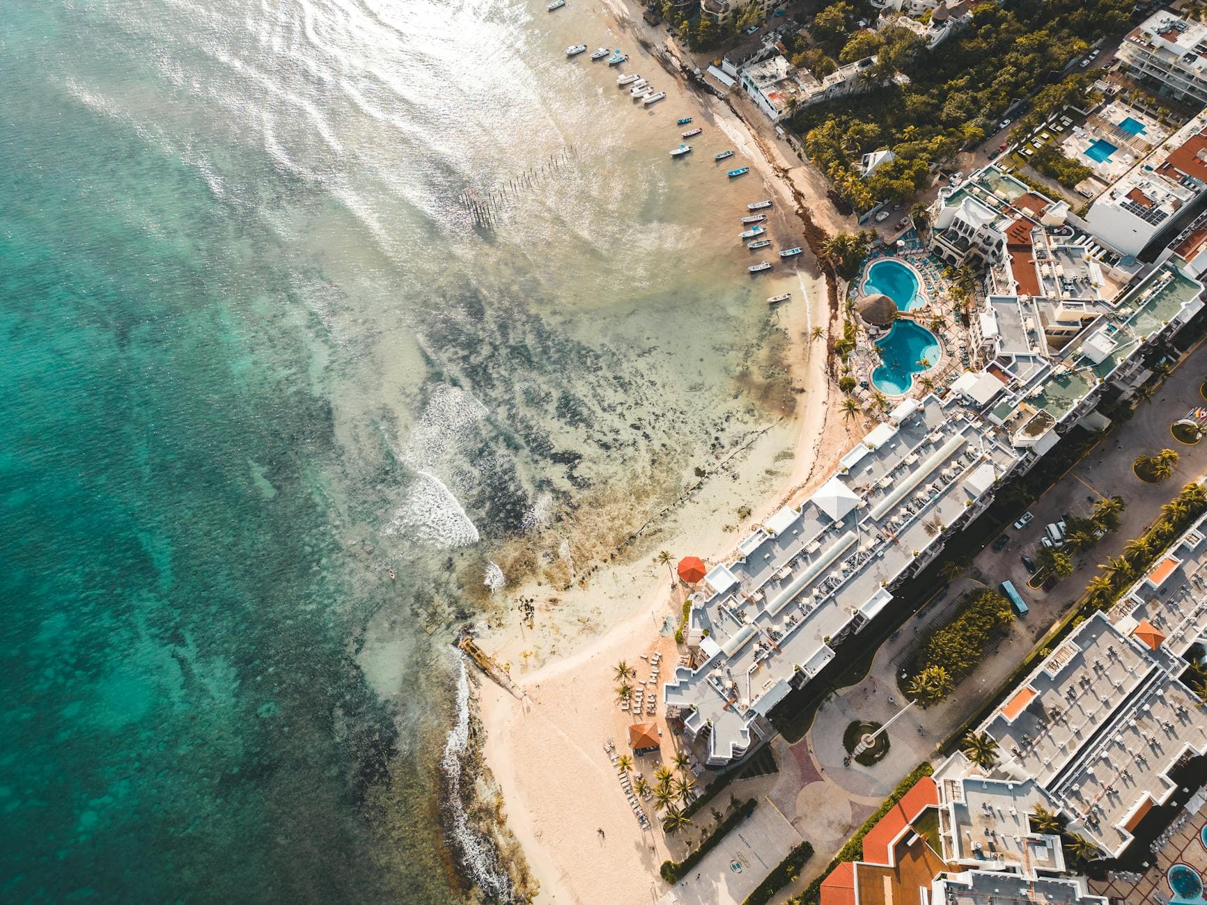 Stunning aerial view of a beachfront resort in Playa del Carmen, showcasing clear waters and sandy beaches.