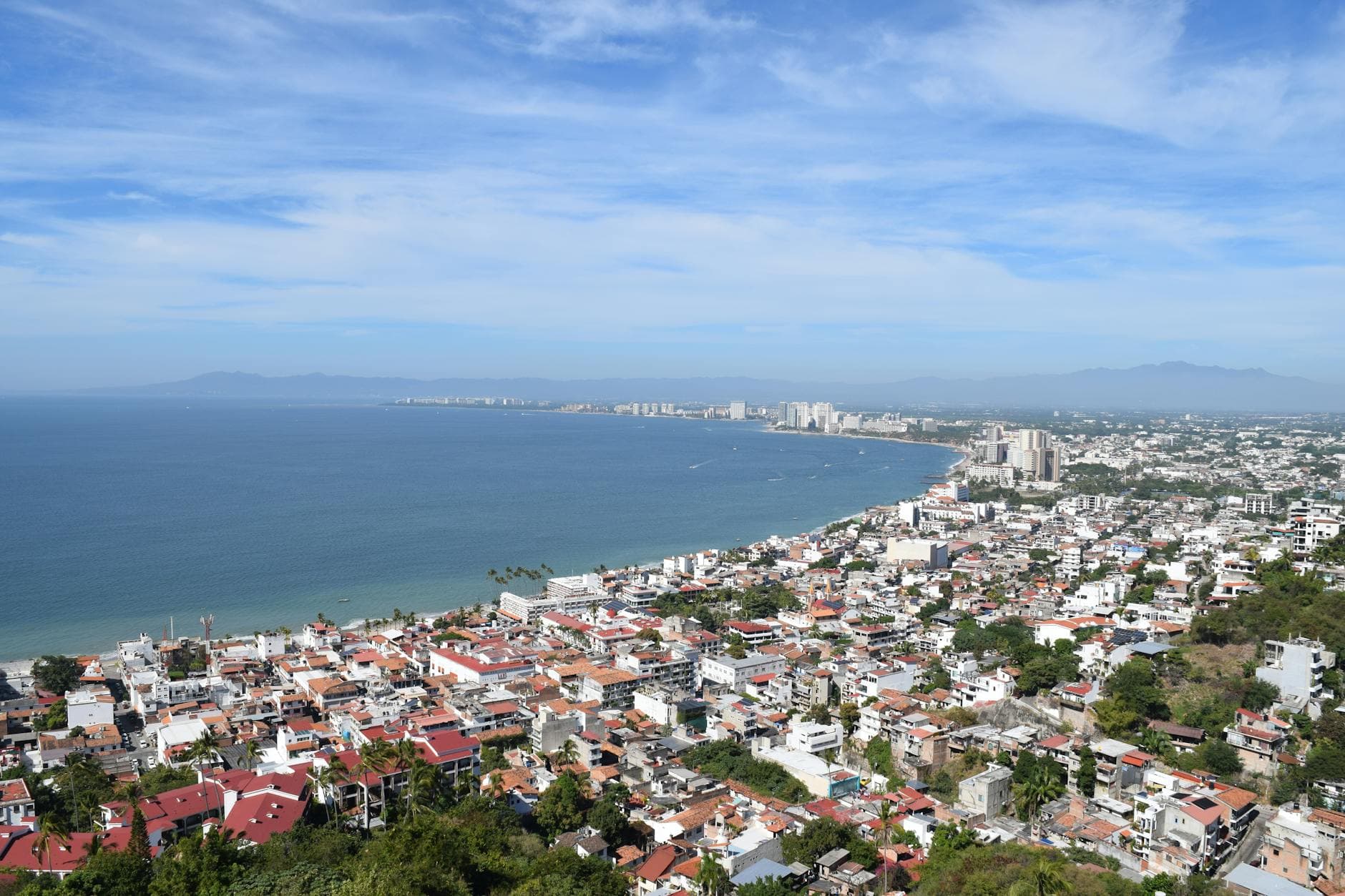 A tranquil day view of Puerto Vallarta's coastline with blue skies and city architecture.