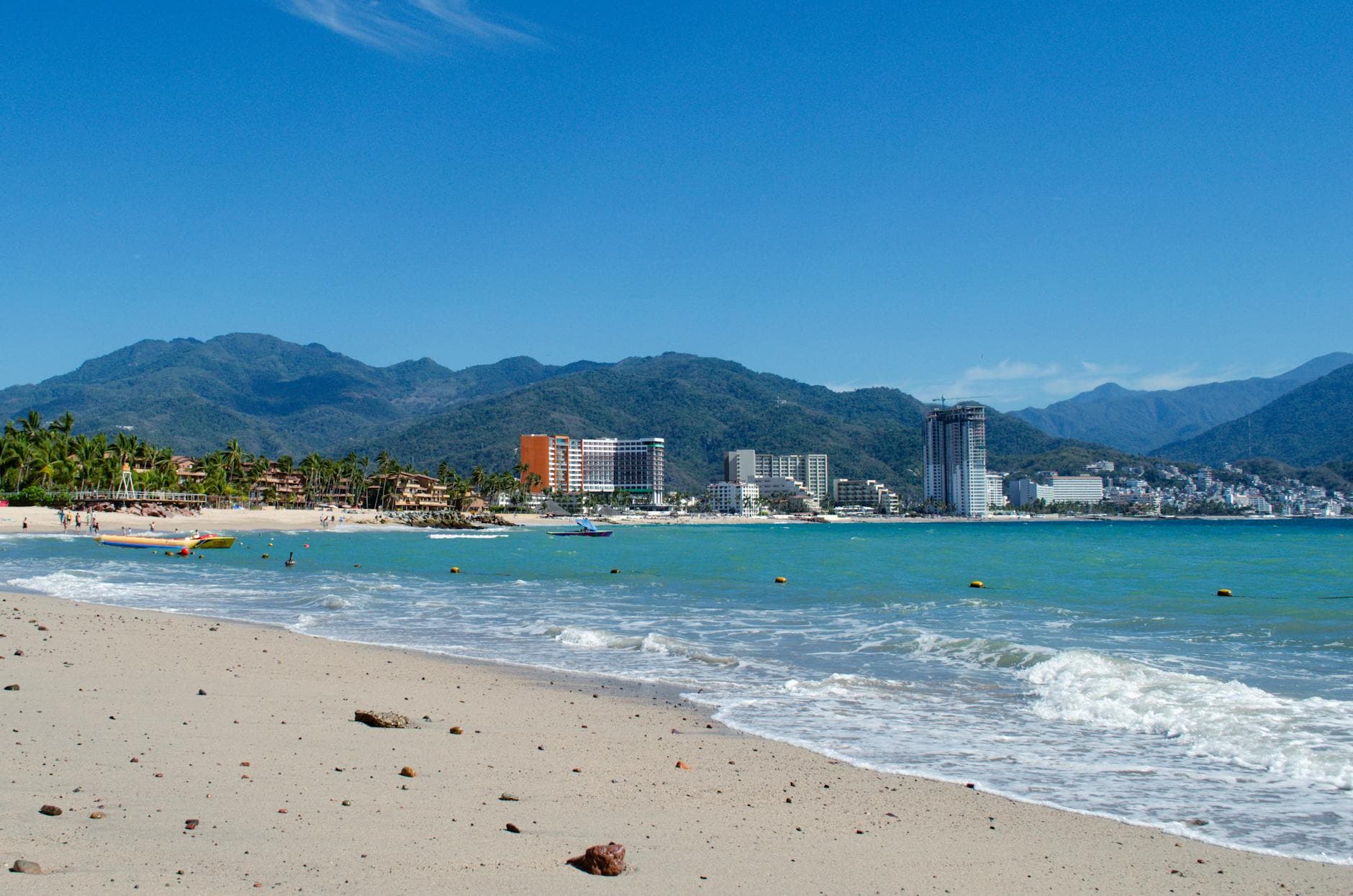 Beautiful beachfront with view of Puerto Vallarta city skyline and surrounding mountains.