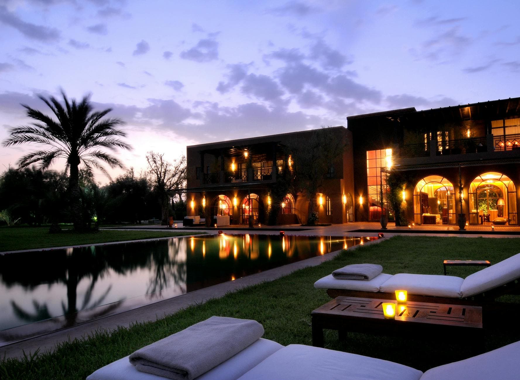 Elegant resort in Marrakech with a serene poolside view and illuminated architecture at dusk.