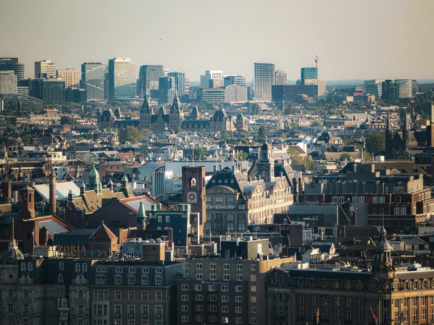 Expansive aerial view of Amsterdam cityscape featuring historic and modern architecture under clear skies.