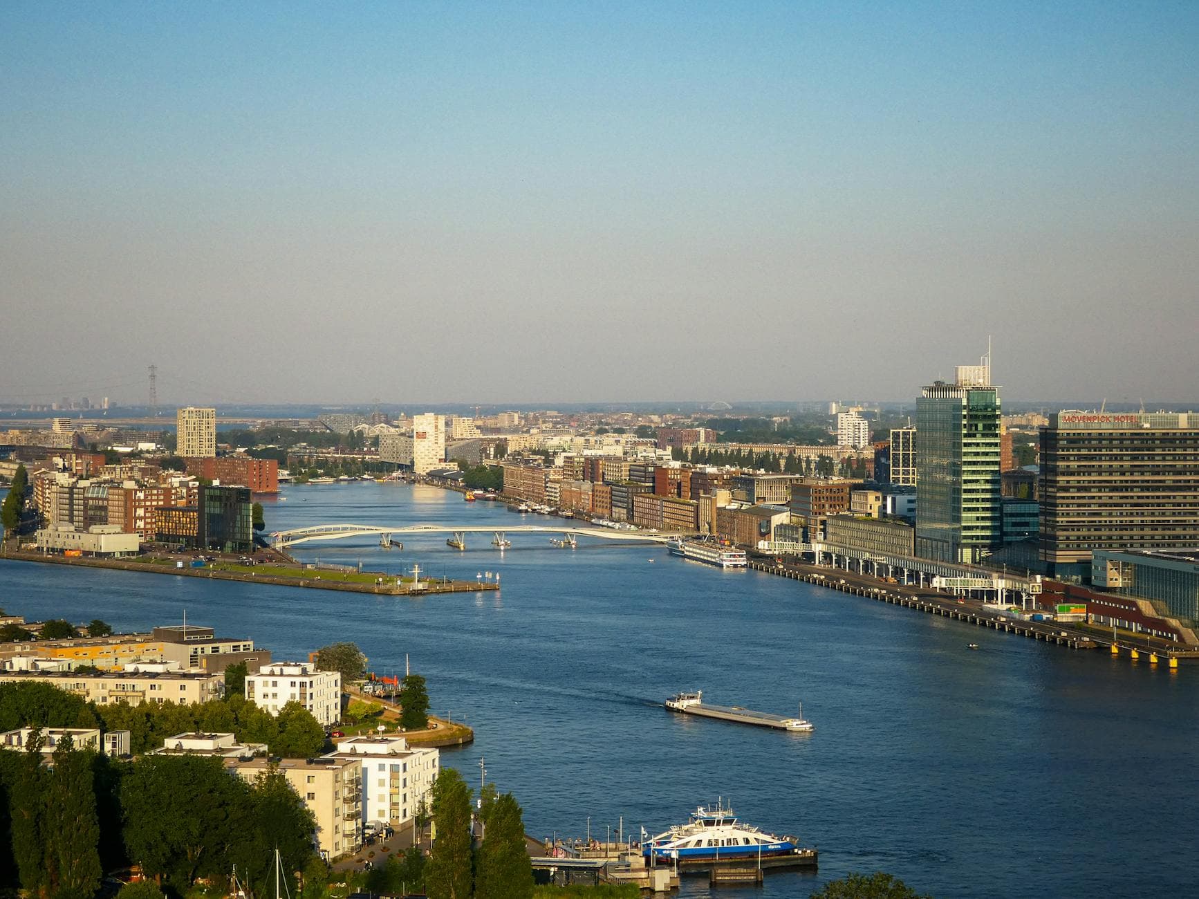 Stunning aerial view of Amsterdam riverfront showcasing modern architecture and waterways.