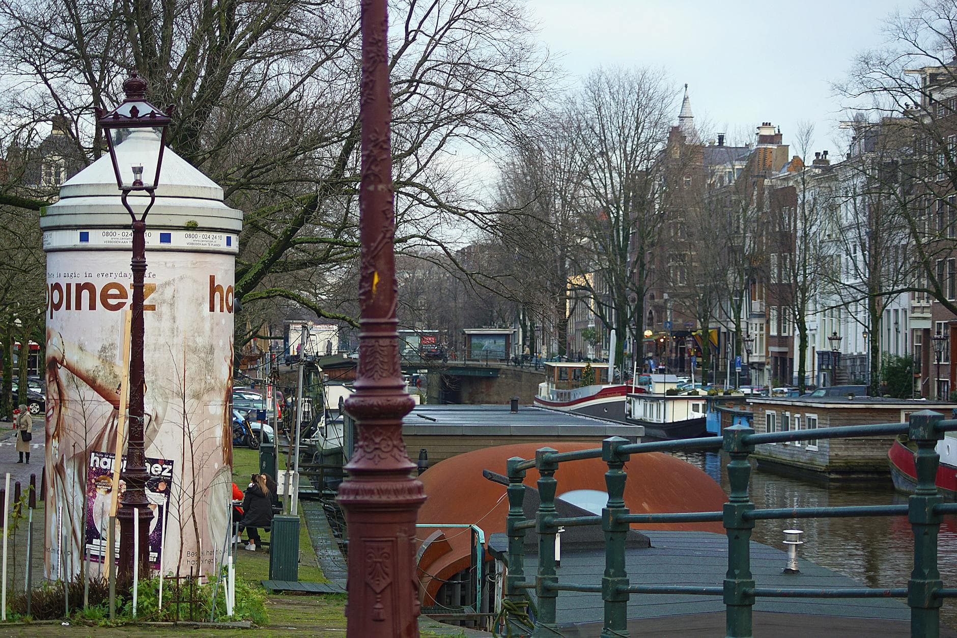 Charming view of Amsterdam's canal with traditional boats and historic buildings under a cloudy sky.