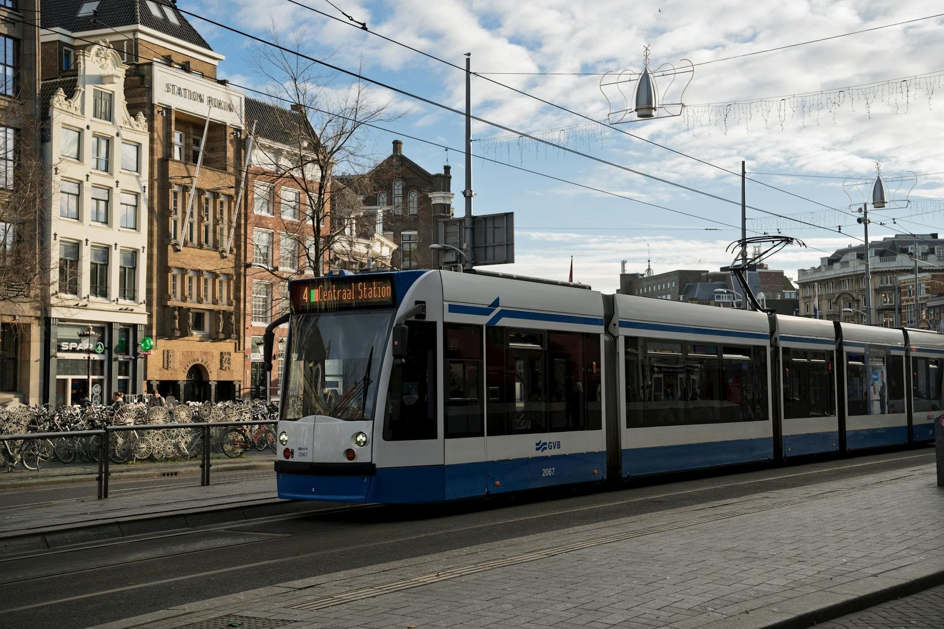 Tram in front of Centraal Station, Amsterdam, showcasing urban architecture and public transport.