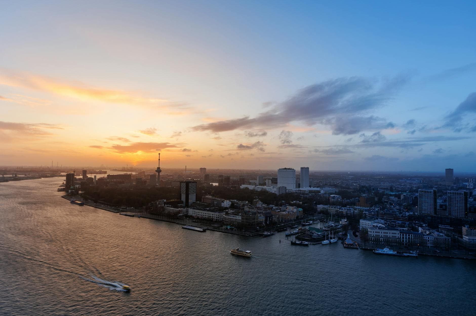 A breathtaking aerial view of Rotterdam skyline at sunset with the iconic Euromast visible.