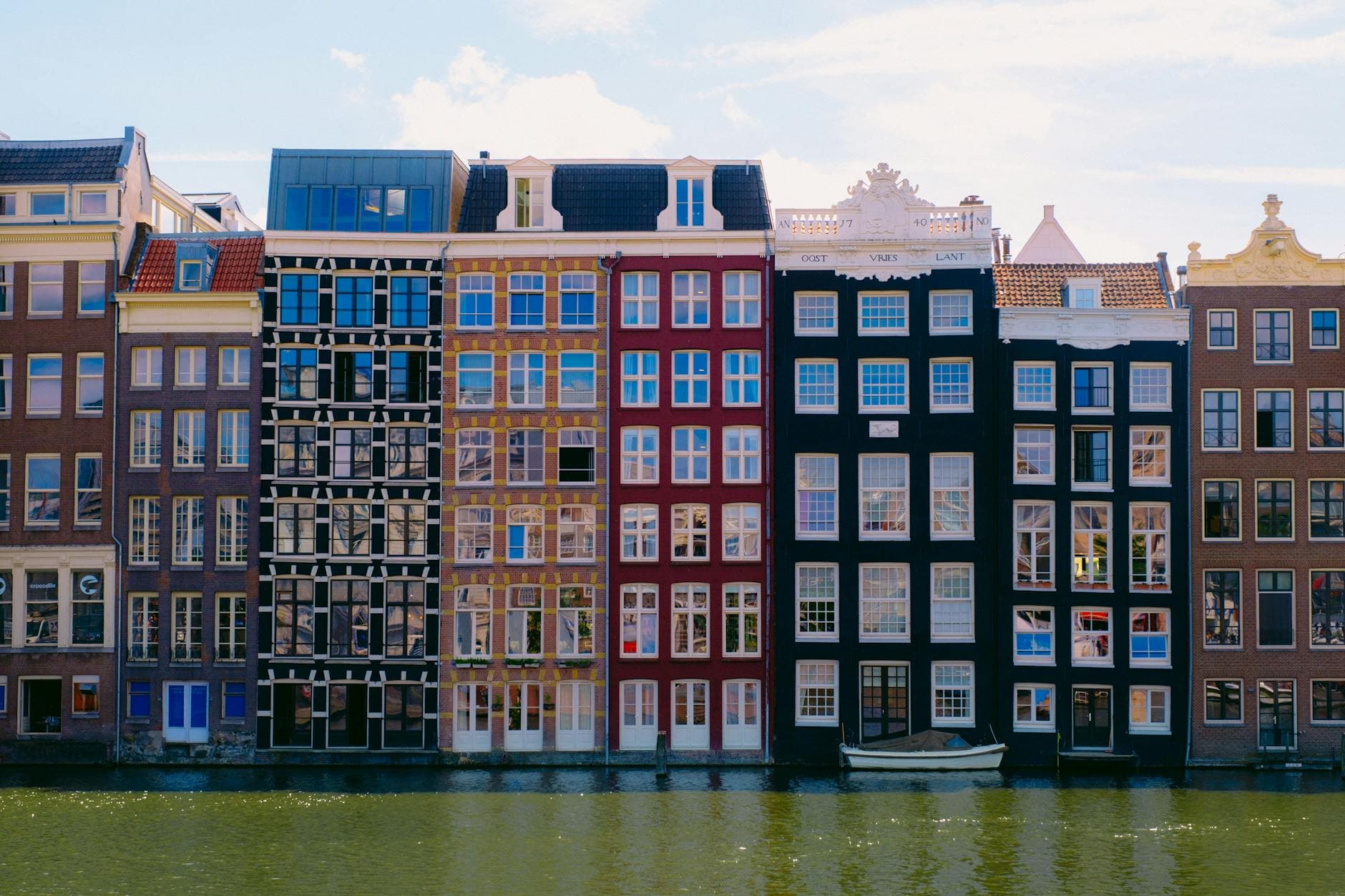Vibrant facades of Amsterdam canal houses reflect in the water.