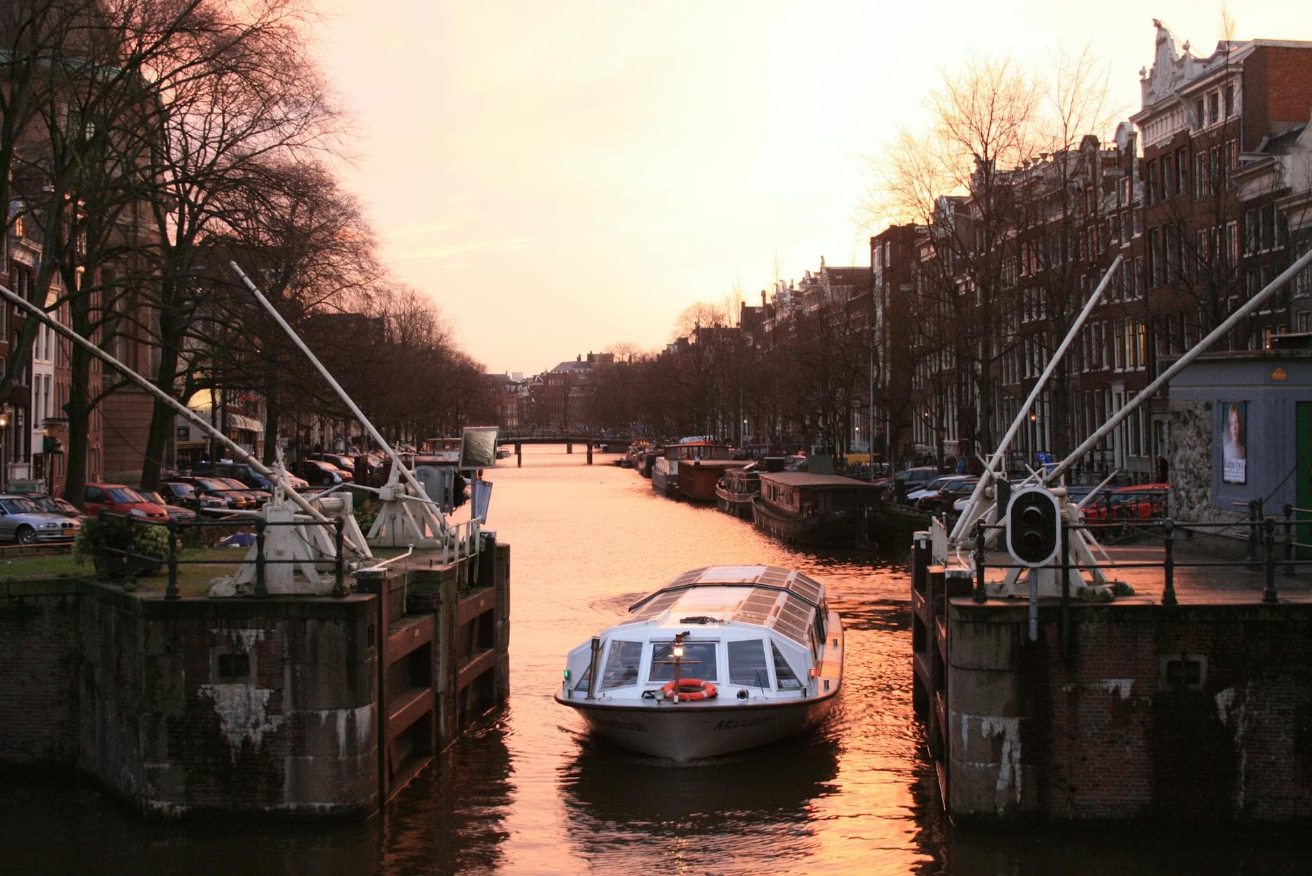 A canal boat navigating through Amsterdam's picturesque canals at sunset, showcasing the city's classic architecture.