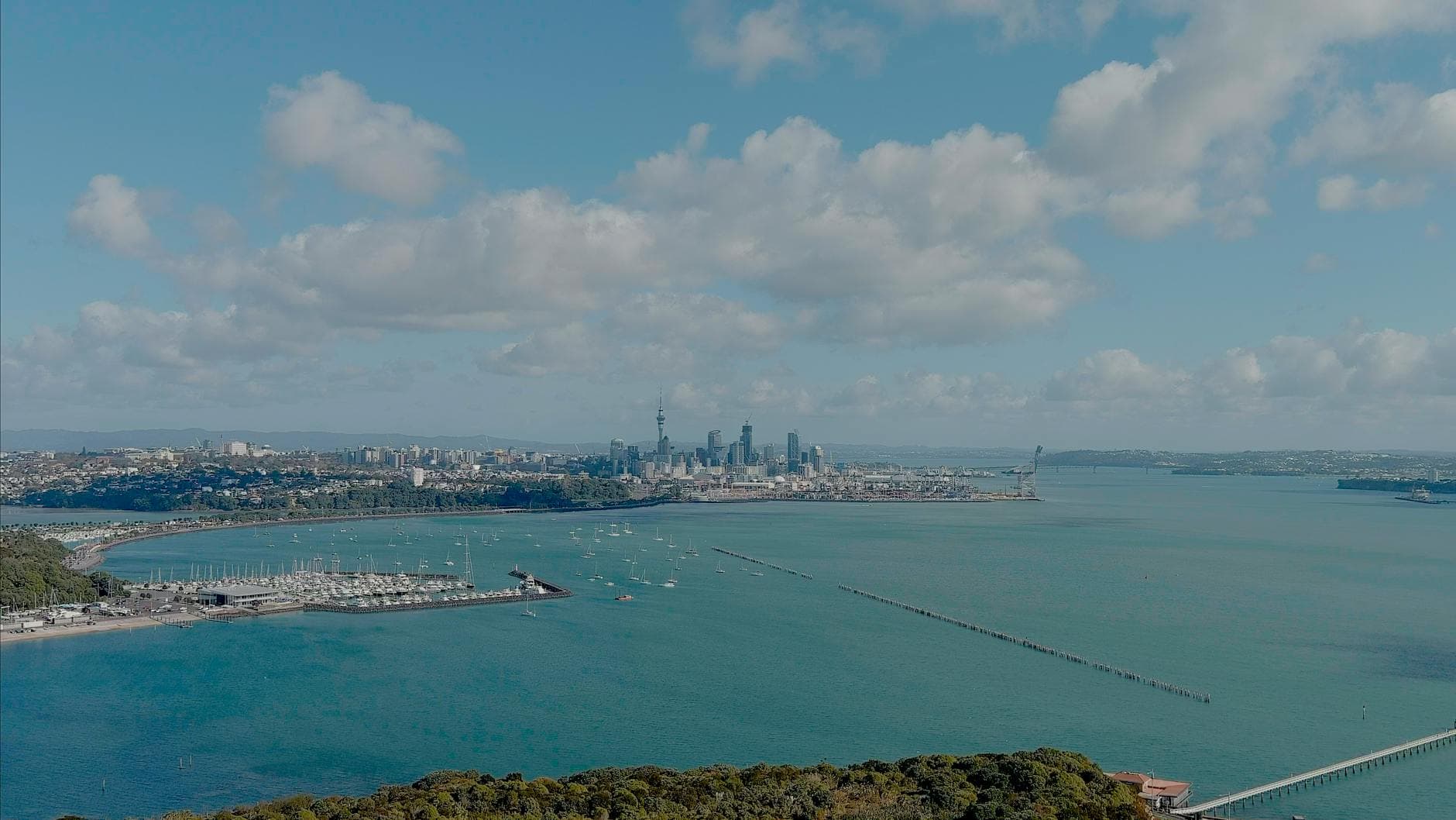 Stunning aerial view of Auckland city skyline and harbor with clear blue sky.