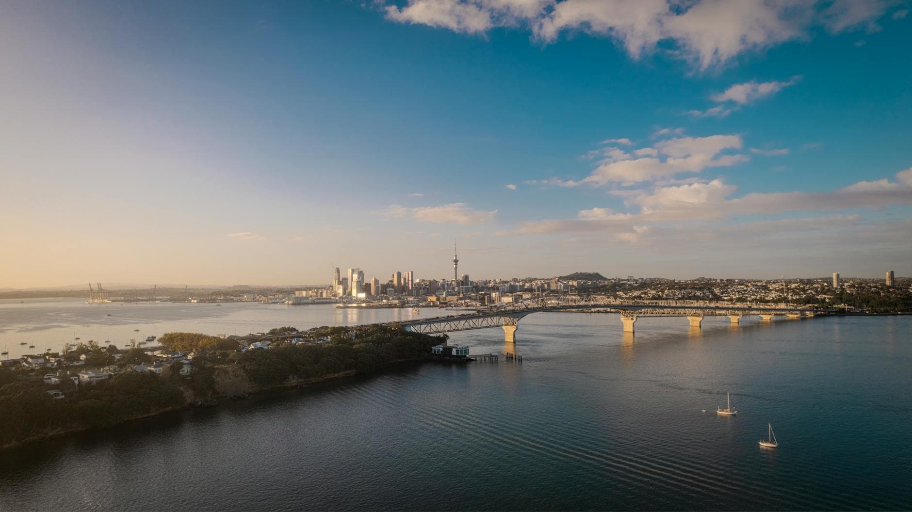Stunning aerial view of Auckland city skyline and Harbor Bridge at sunset.