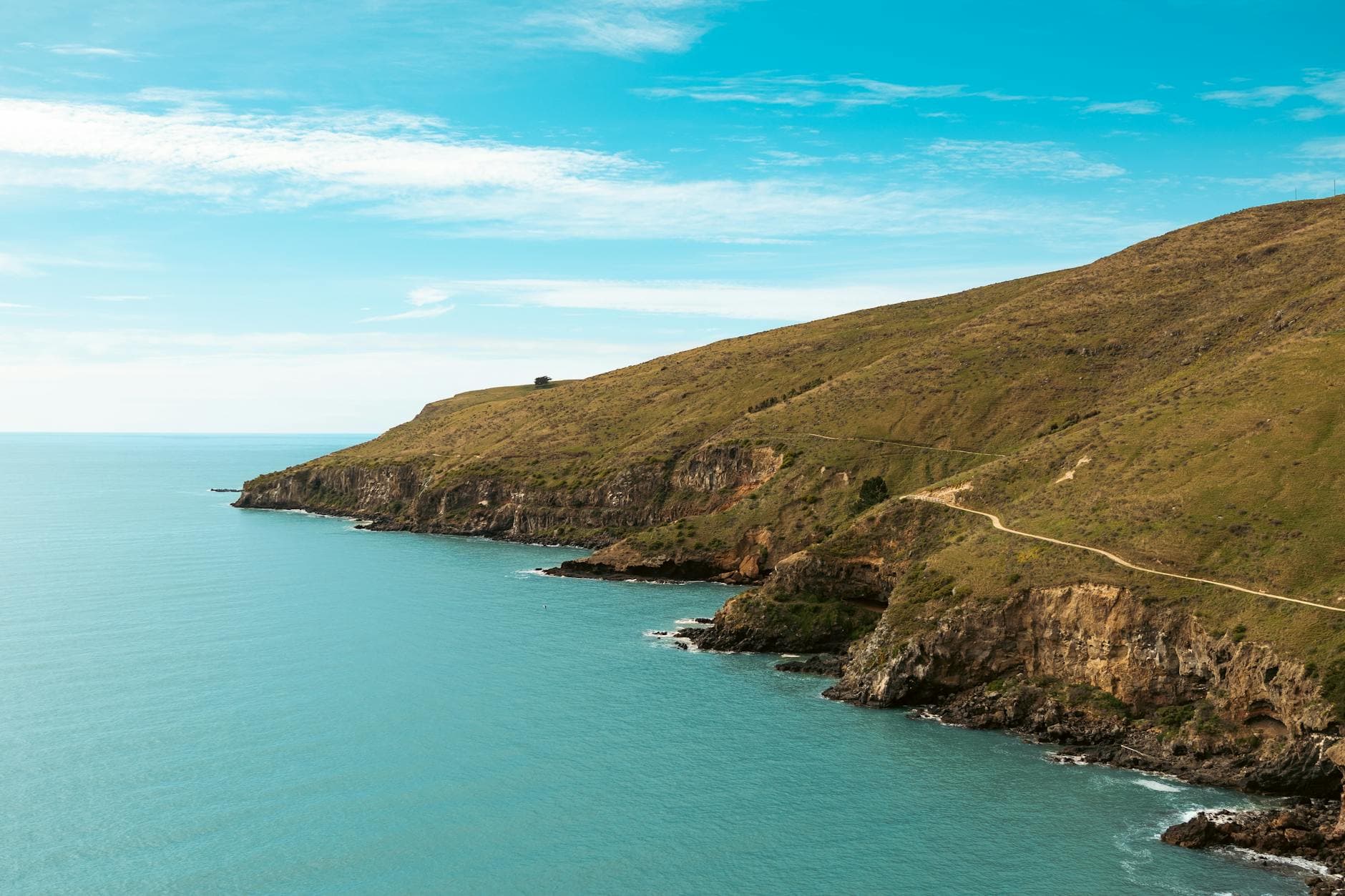 Breathtaking view of coastal cliffs in Christchurch, New Zealand with clear blue skies and ocean reflections.