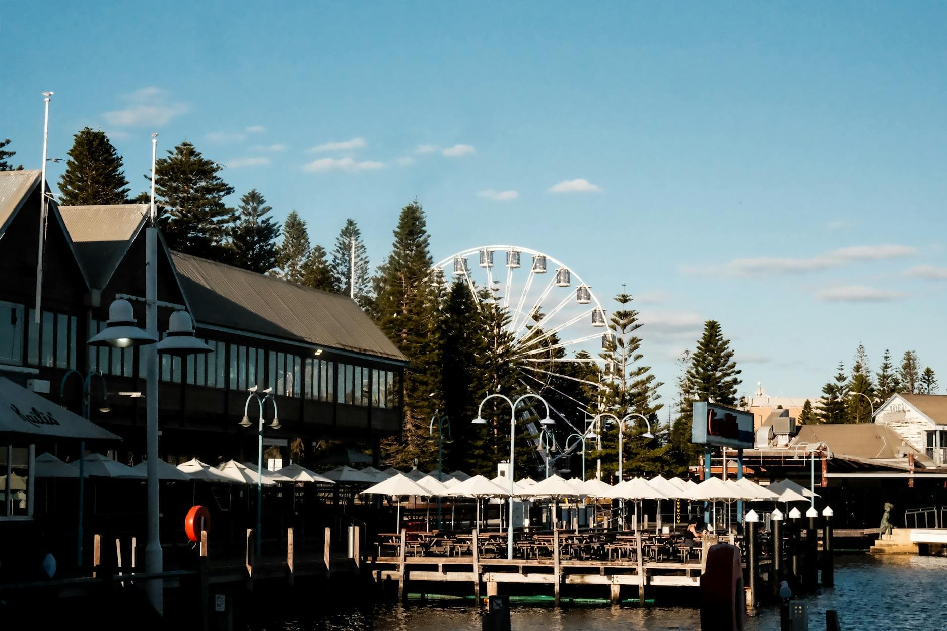 A captivating photo of Fremantle's waterfront with a Ferris wheel and modern architecture under a clear blue sky.