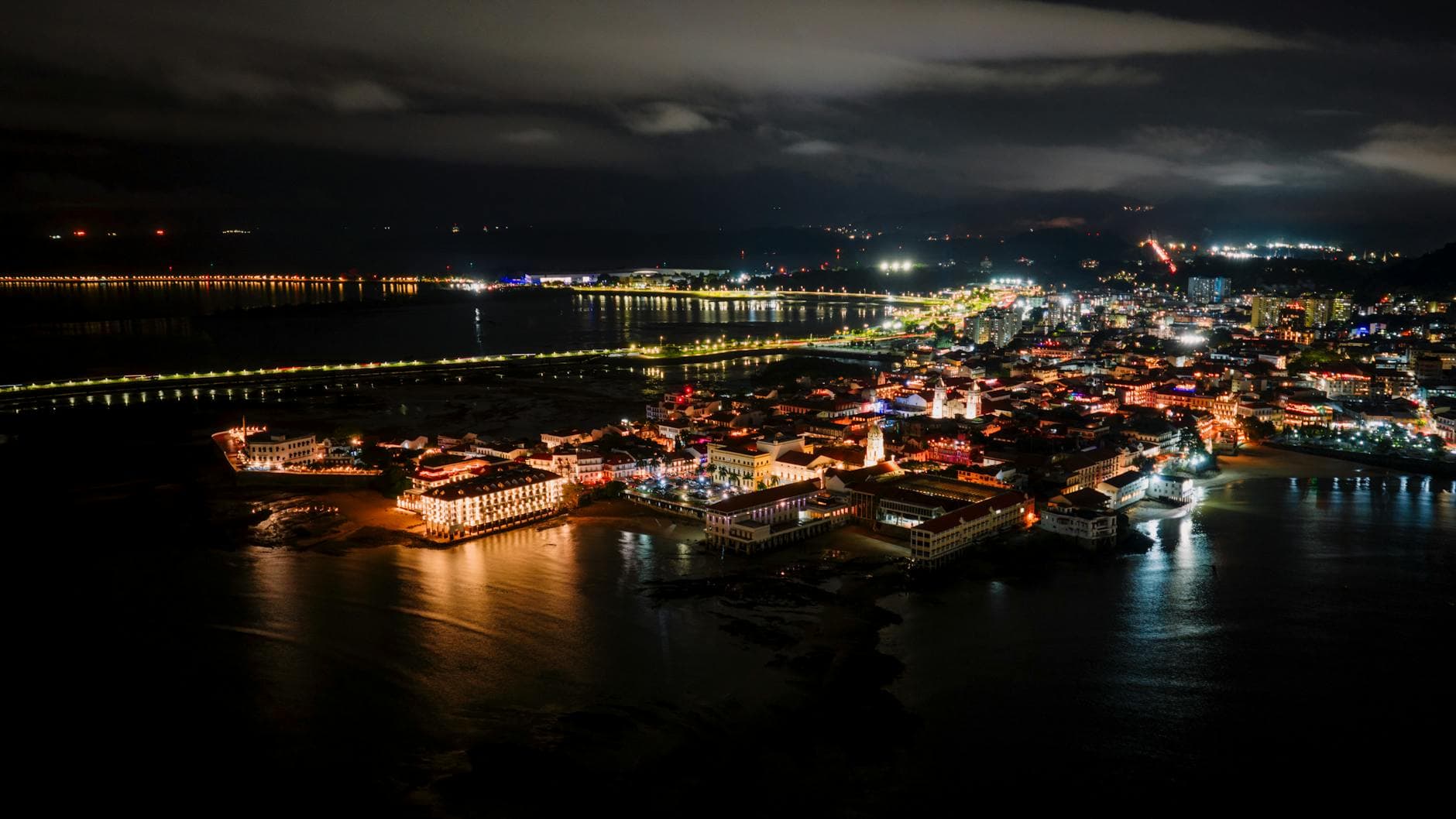 Captivating aerial night view of Panama City's illuminated waterfront with city skyline against the dark sky.