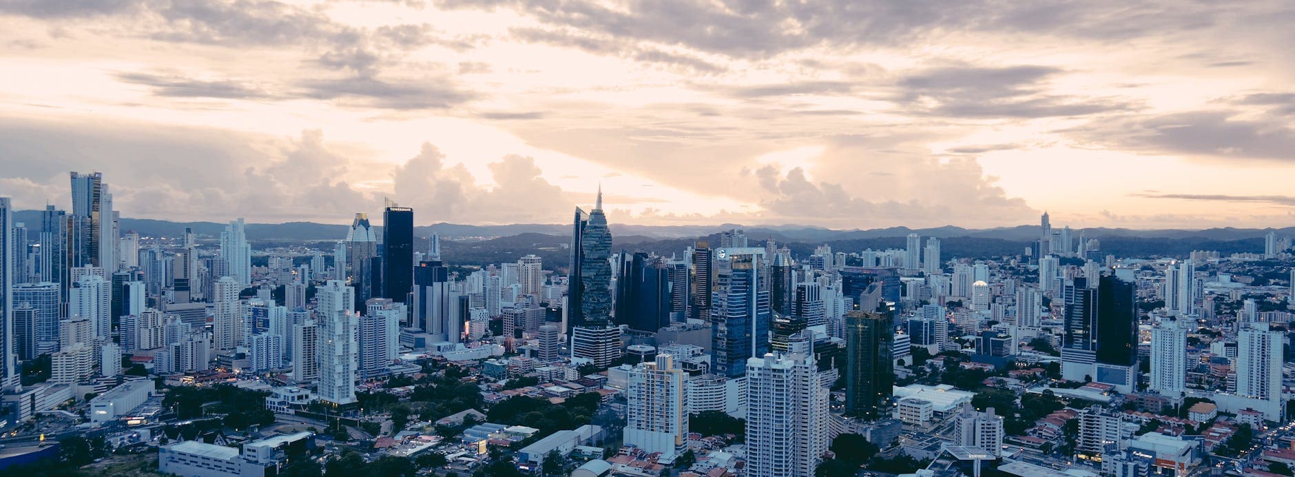 A stunning aerial view of Panama City showcasing its modern skyscrapers at sunset under an overcast sky.