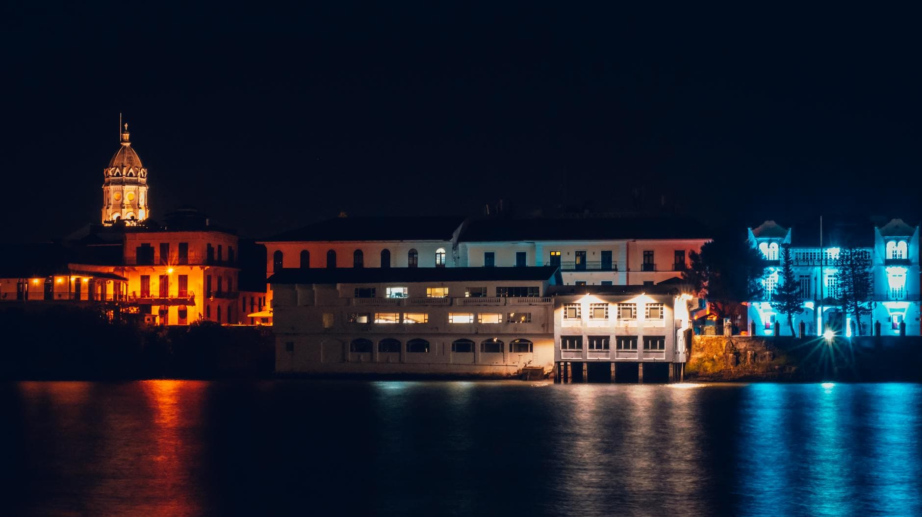 Stunning night view of Panama City's waterfront with illuminated historic buildings reflecting on the water.