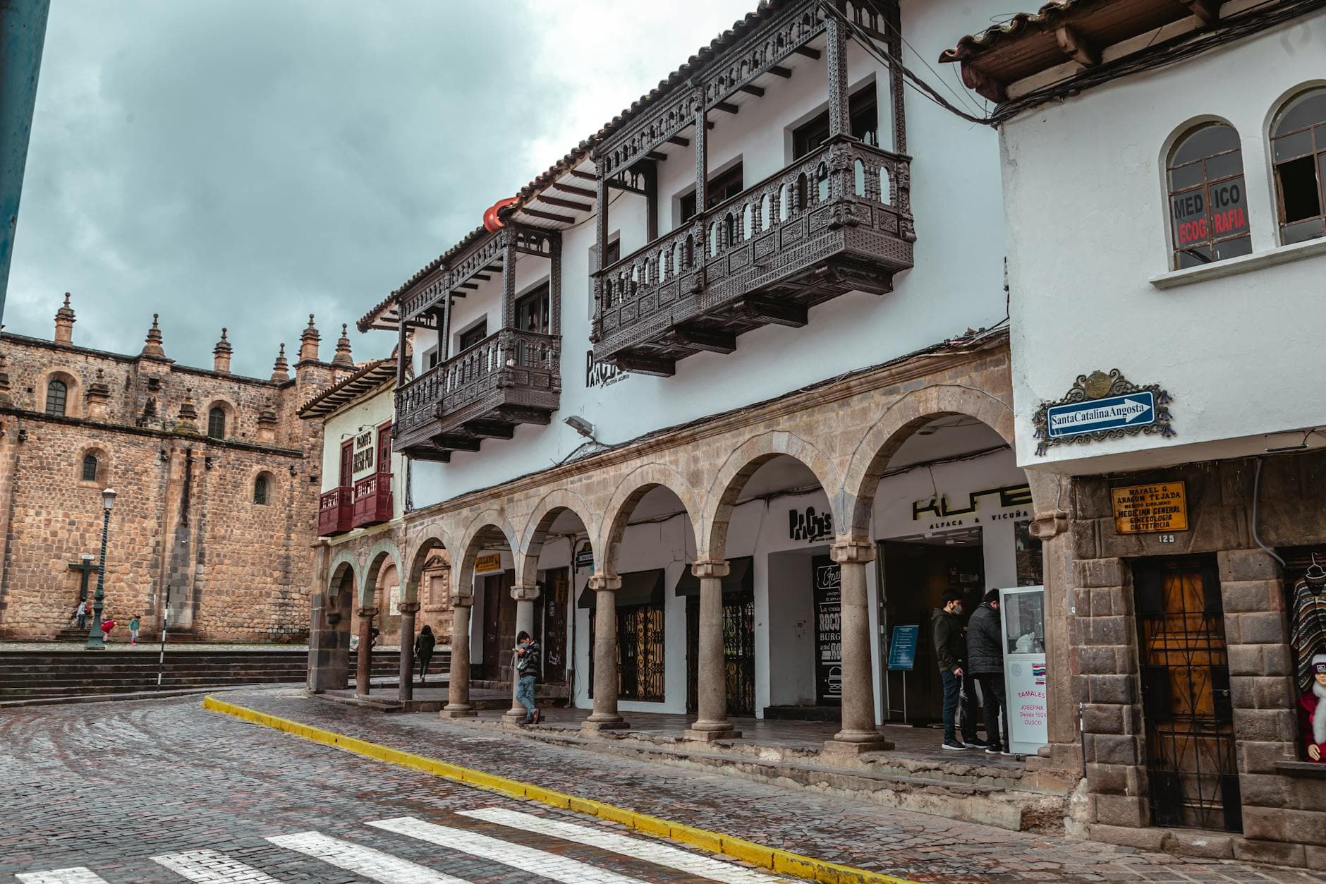 Street view of colonial buildings in Cusco, showcasing traditional balconies and cobblestone streets.