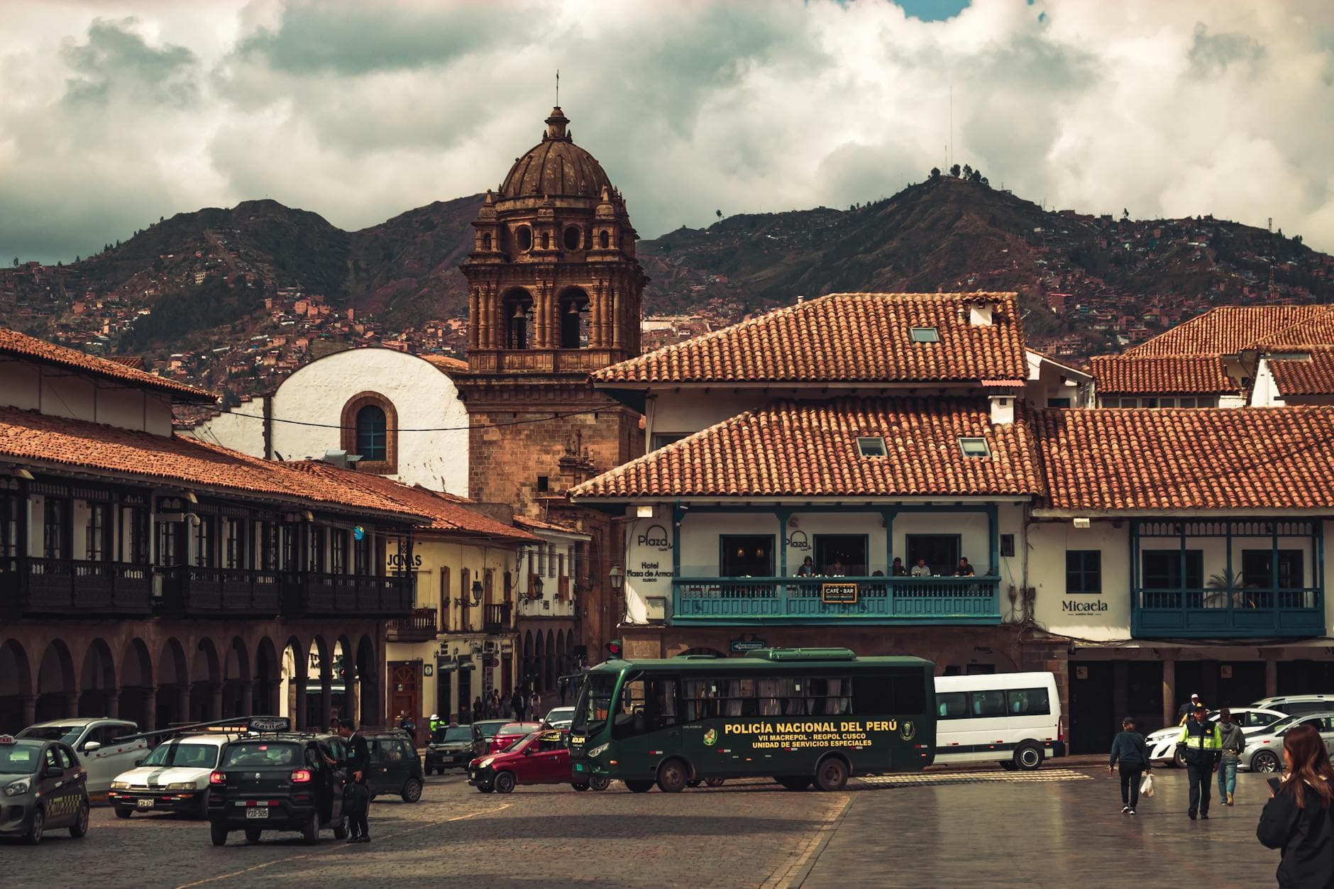 Scenic view of a historic town square in Cusco, Peru, showcasing colonial architecture with mountainous backdrop.