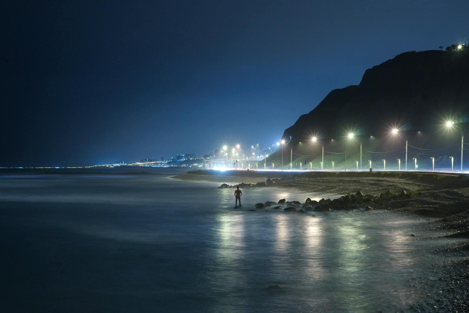 Serene night view of Callao beach with glowing streetlights and a quiet shoreline in Lima, Peru.