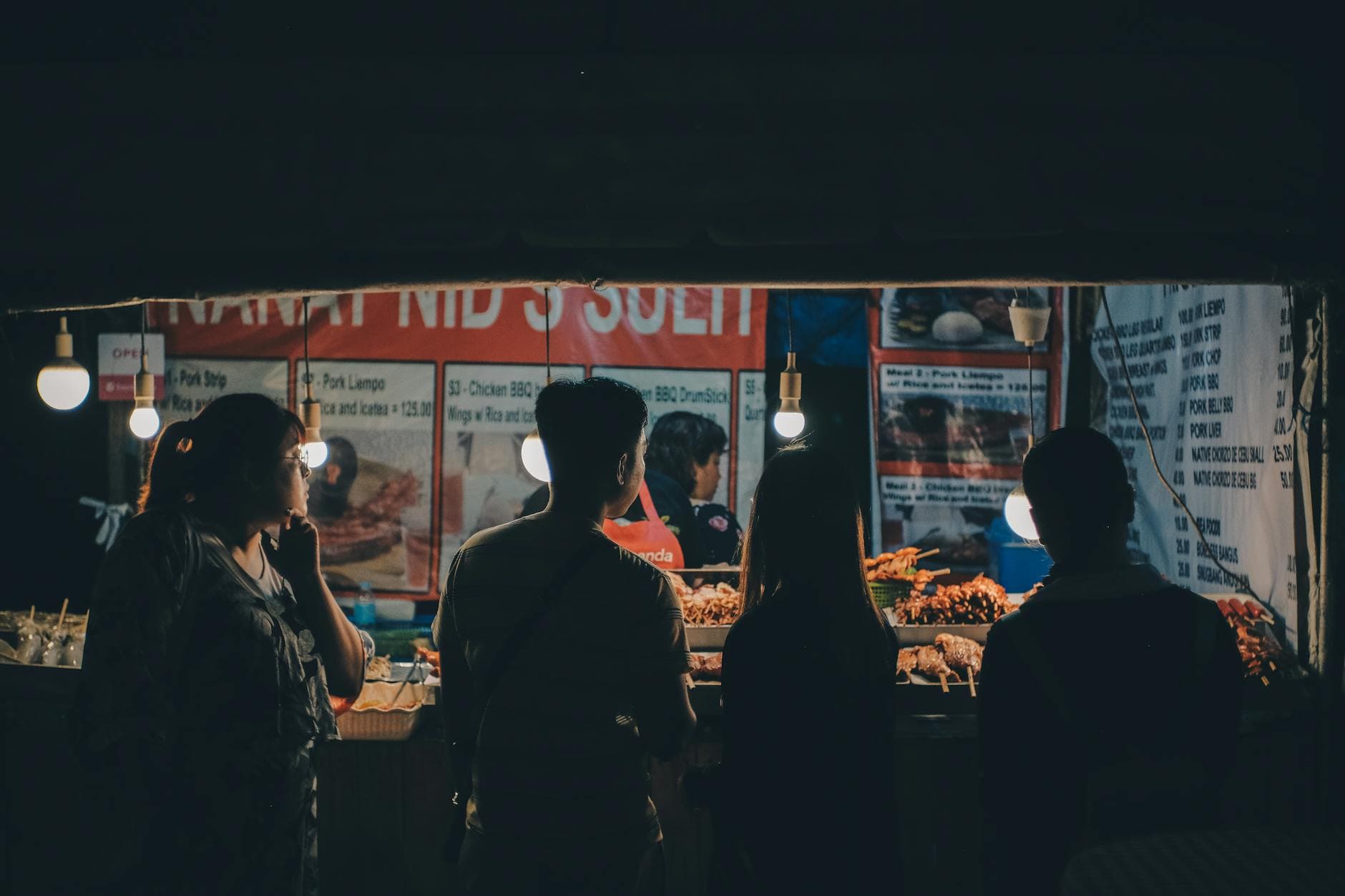 A vibrant night street food market in Cebu City with people enjoying Asian cuisine.