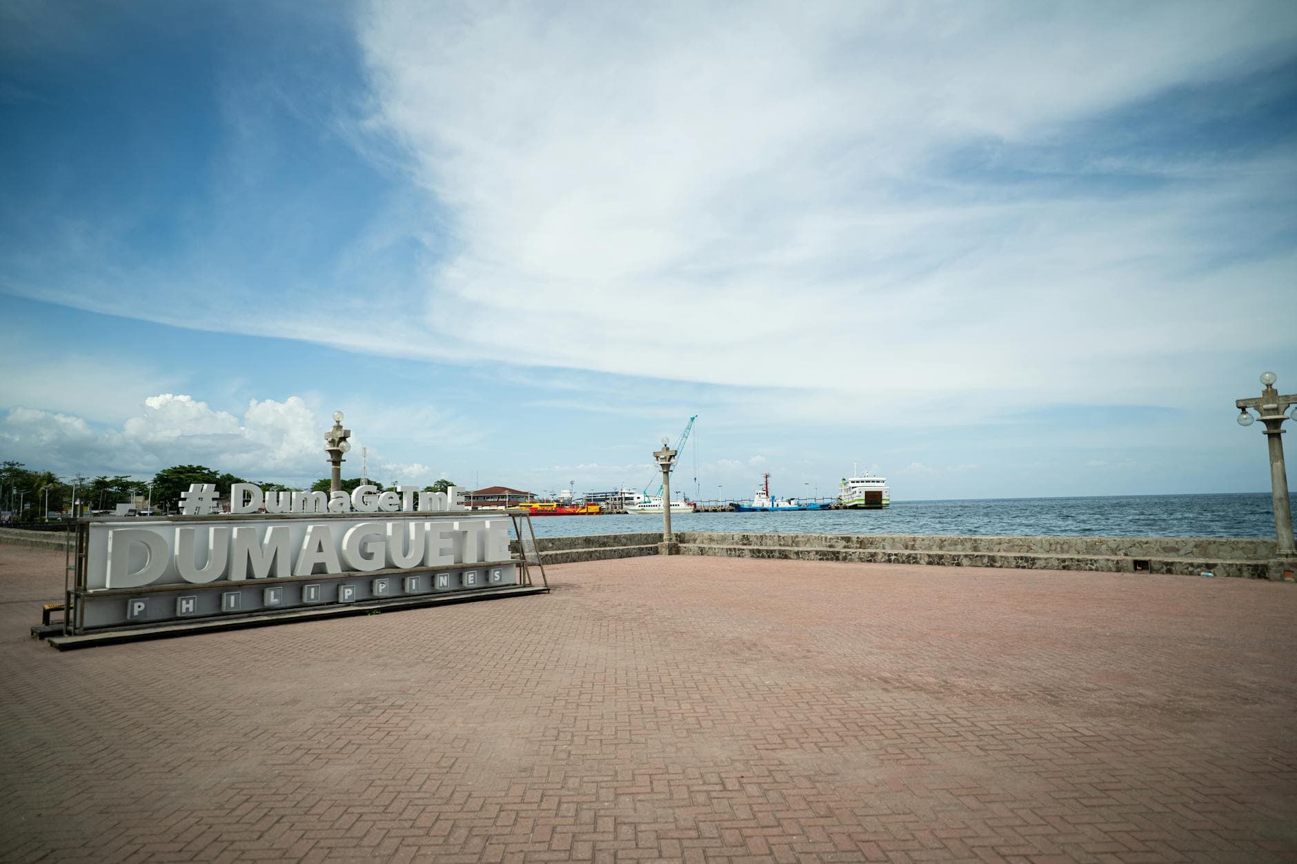 Scenic view of Dumaguete City harbor with iconic sign and ocean backdrop on a sunny day.