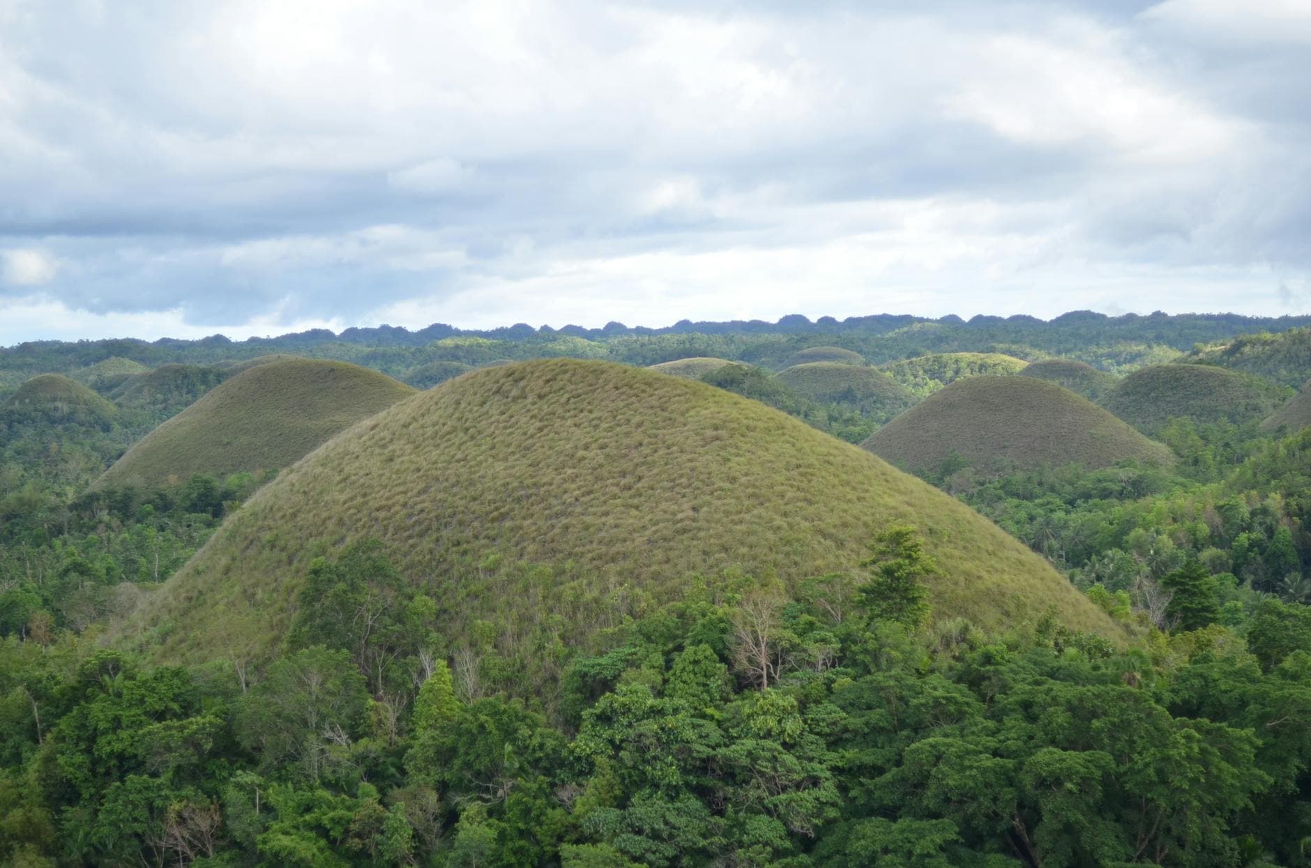 Experience the iconic Chocolate Hills of Bohol under a cloudy sky, Central Visayas.