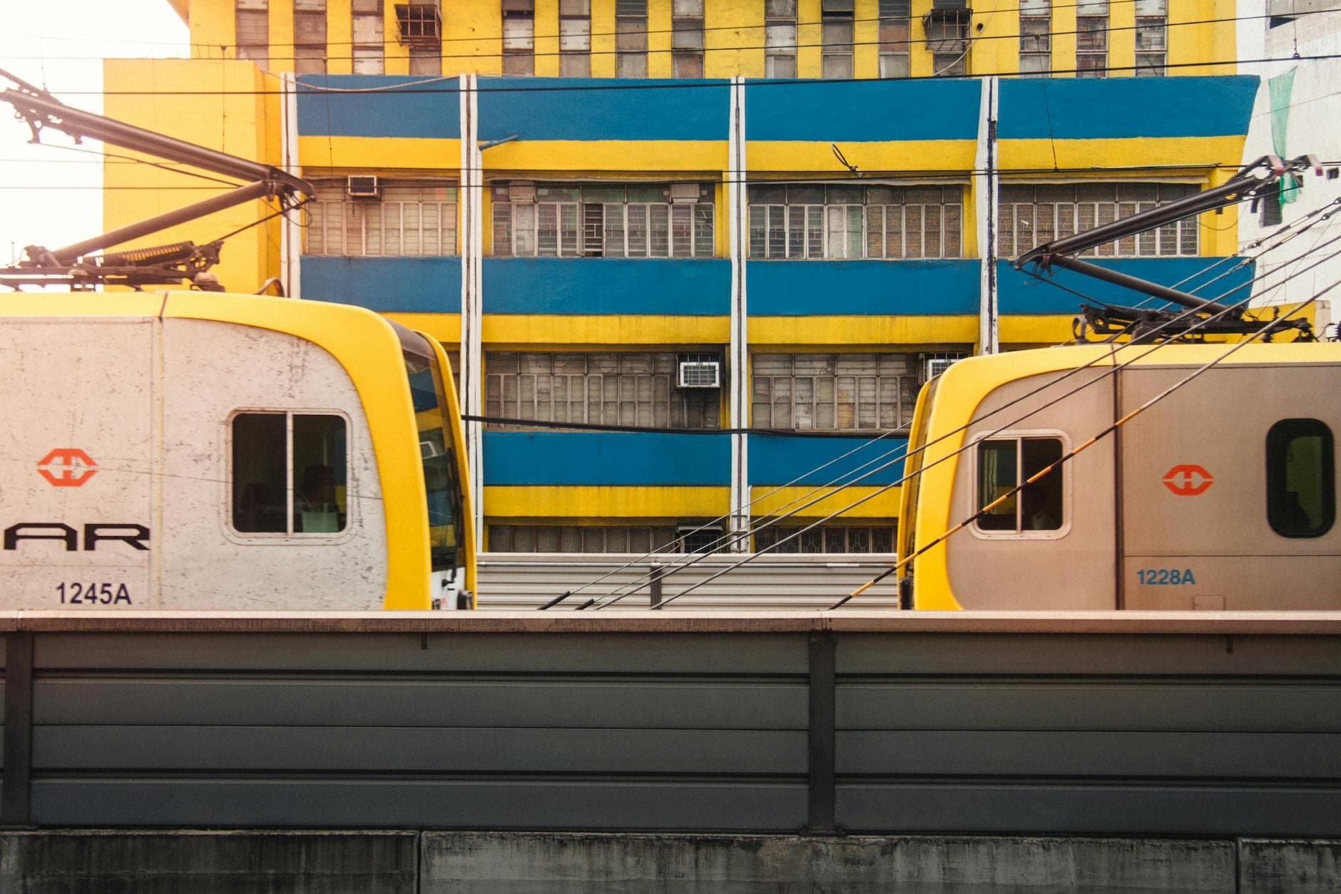 Lively urban scene of yellow trains against a vibrant building in Manila, Philippines.