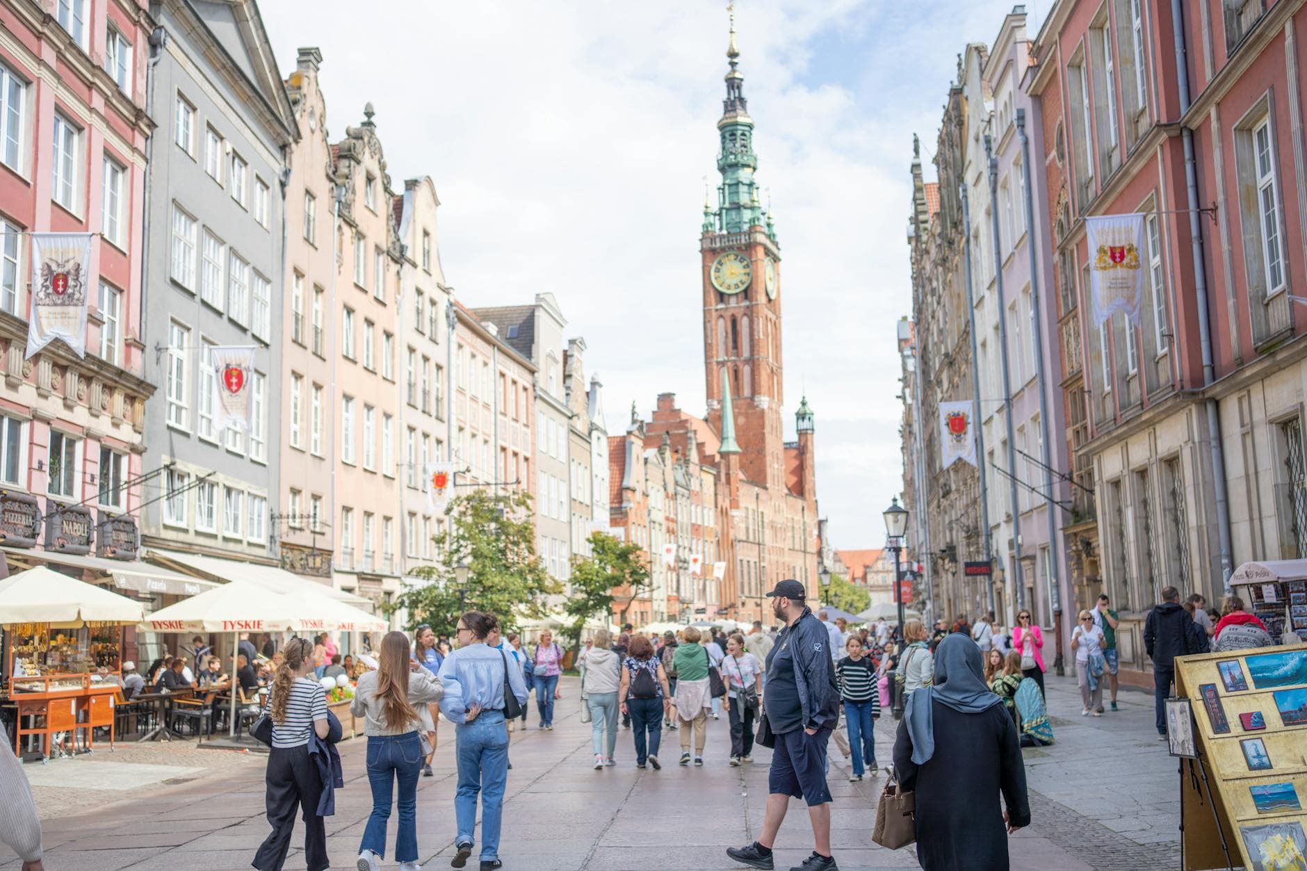 Discover the vibrant atmosphere of Long Street in Gdańsk, Poland, bustling with locals and tourists alike on a sunny day.