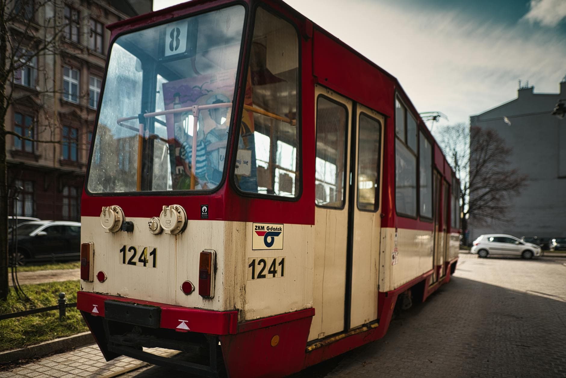 Retro red tram with number 1241 on the street, set against urban buildings, evokes nostalgia.