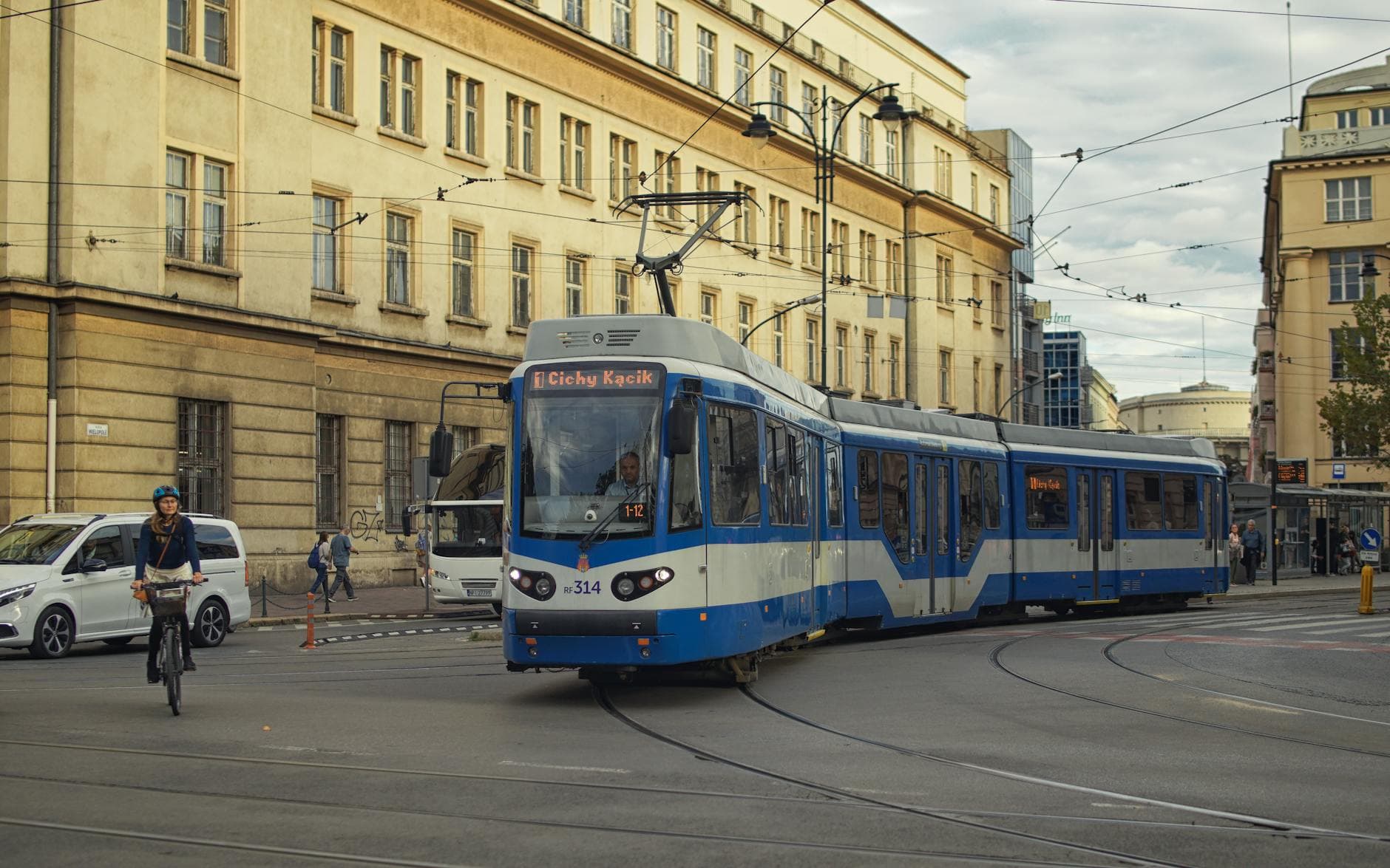Blue tram navigating the streets of Kraków, Poland with urban architecture backdrop.