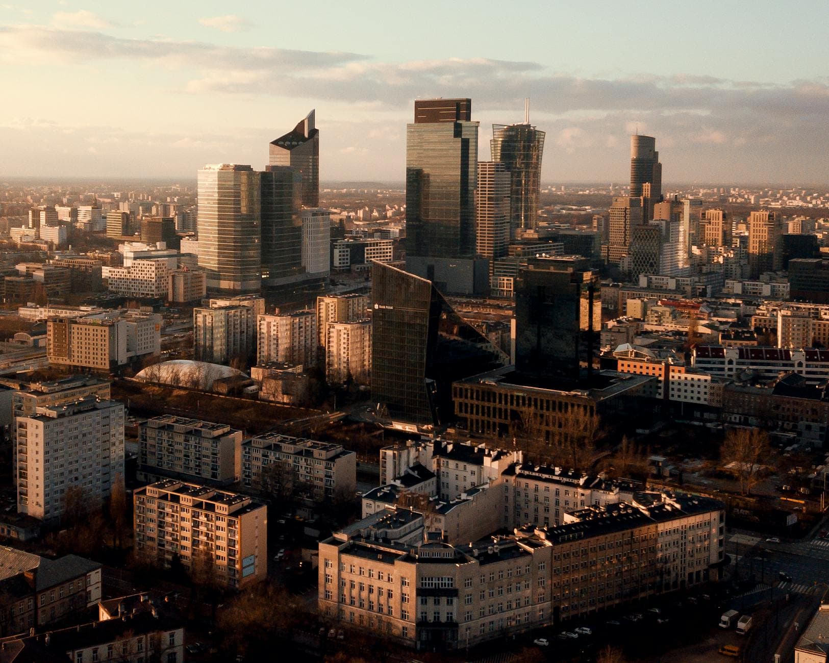 Aerial shot of Warsaw's skyline showcasing modern skyscrapers and urban landscape at sunset.