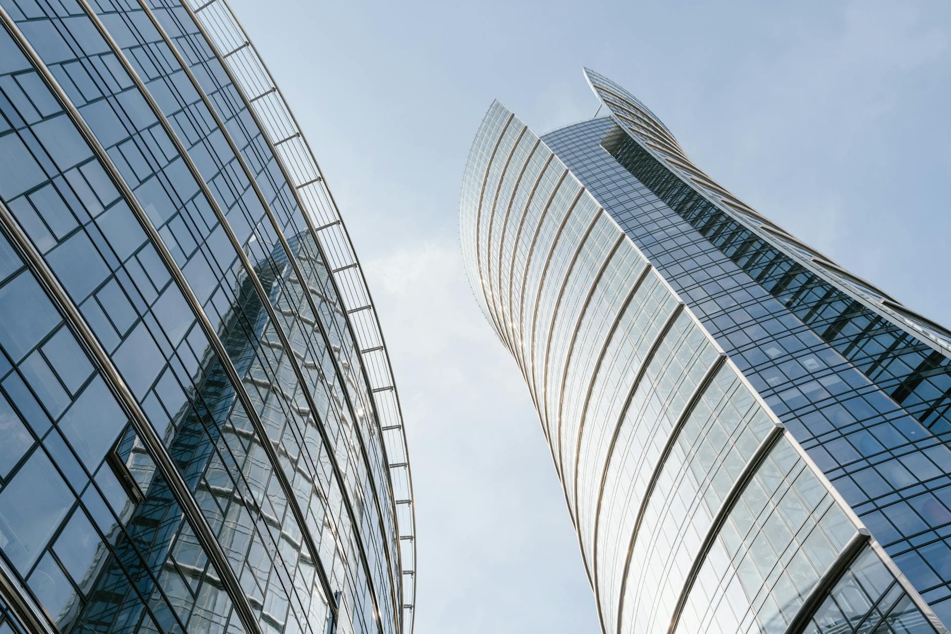 Low-angle view of modern glass skyscrapers in Warsaw, Poland against a clear blue sky.