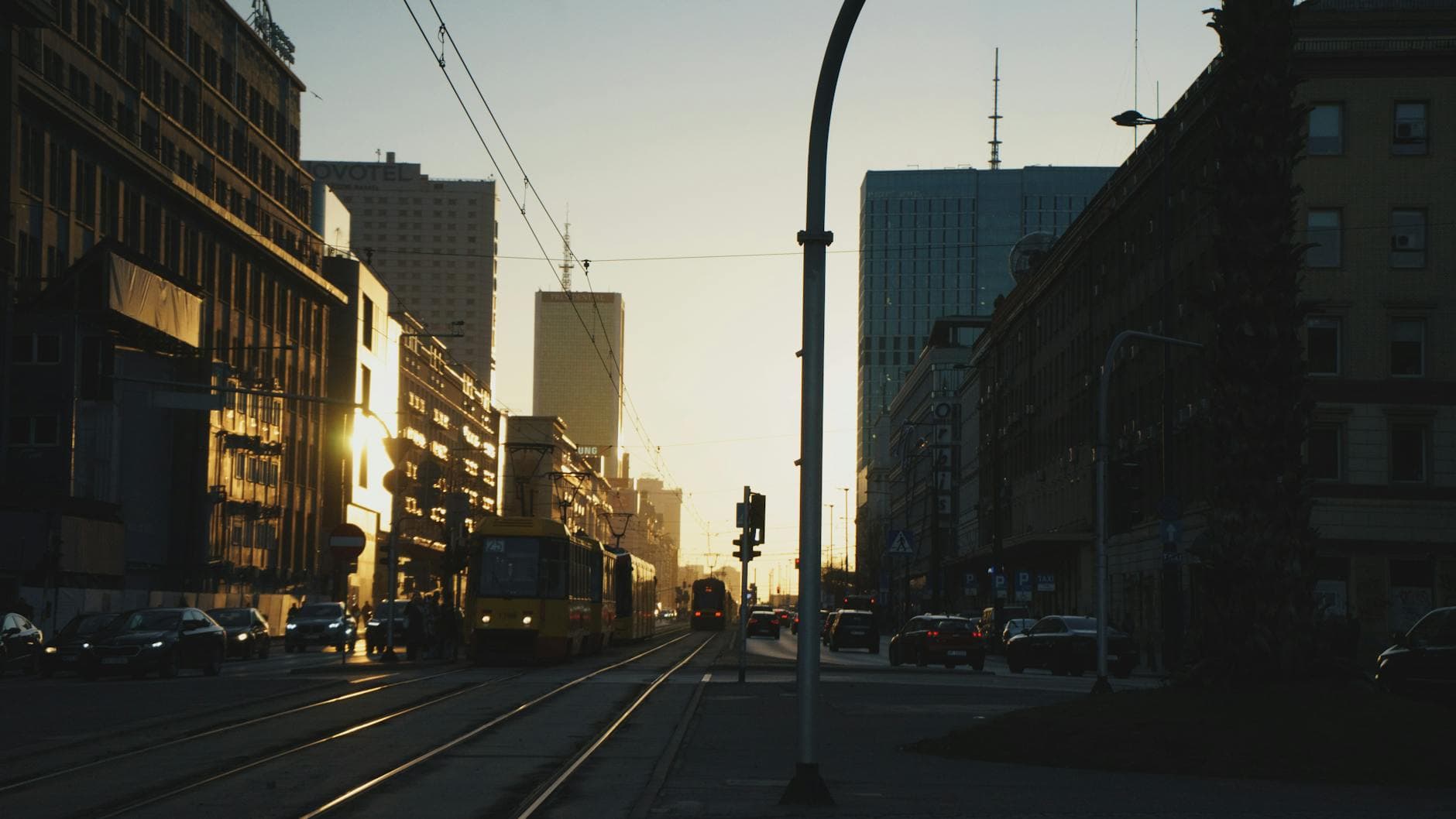 Captivating sunset over Warsaw's downtown, highlighting the silhouette of buildings and a passing tram.