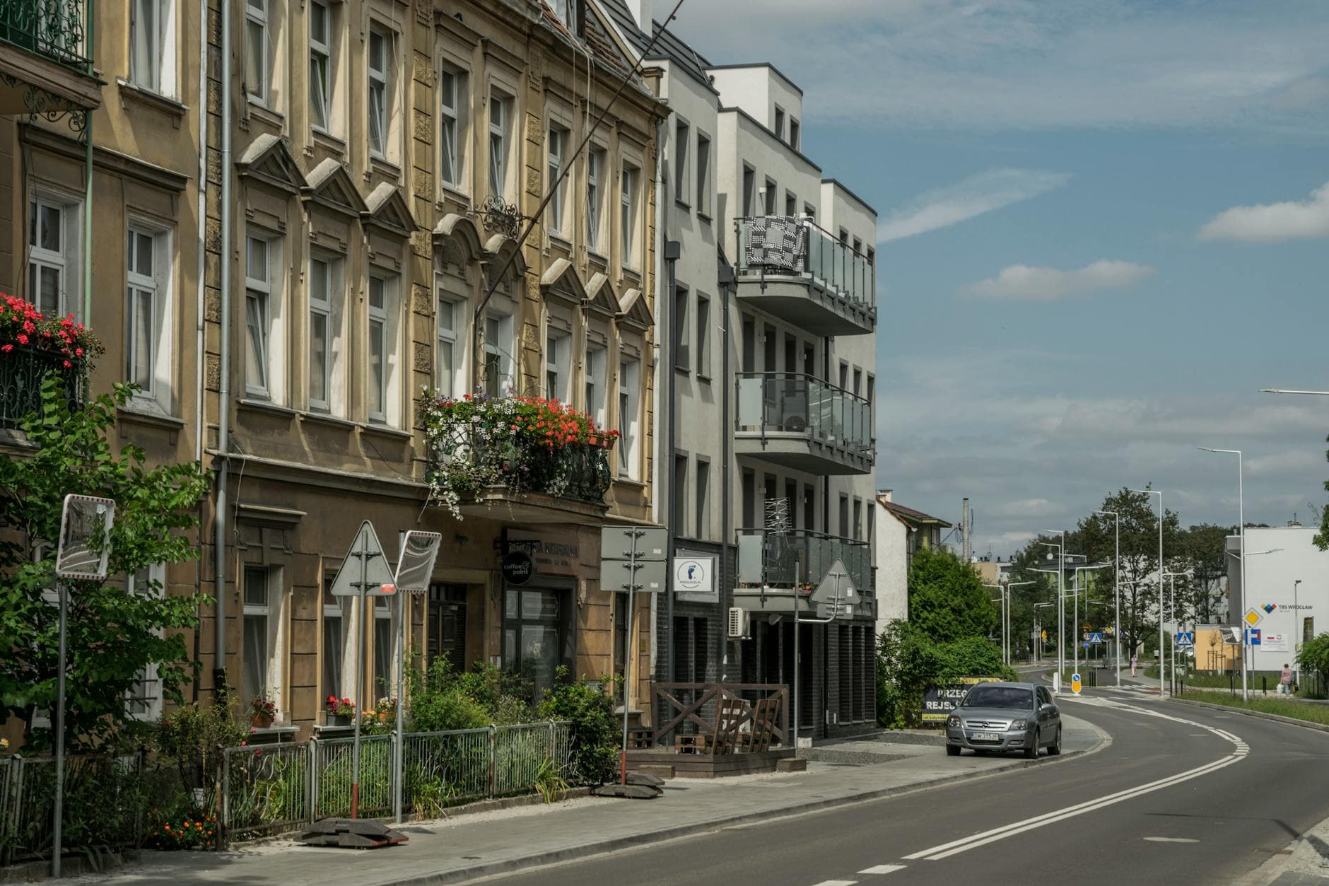 Street view of residential buildings and a car in Wrocław, showcasing city life.