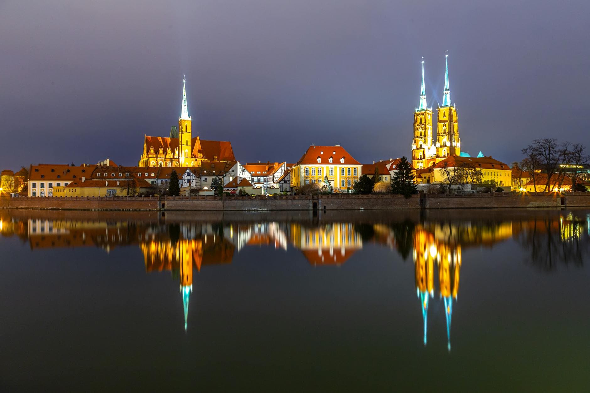 Stunning night view of Wrocław Cathedral illuminated and mirrored in the calm river.