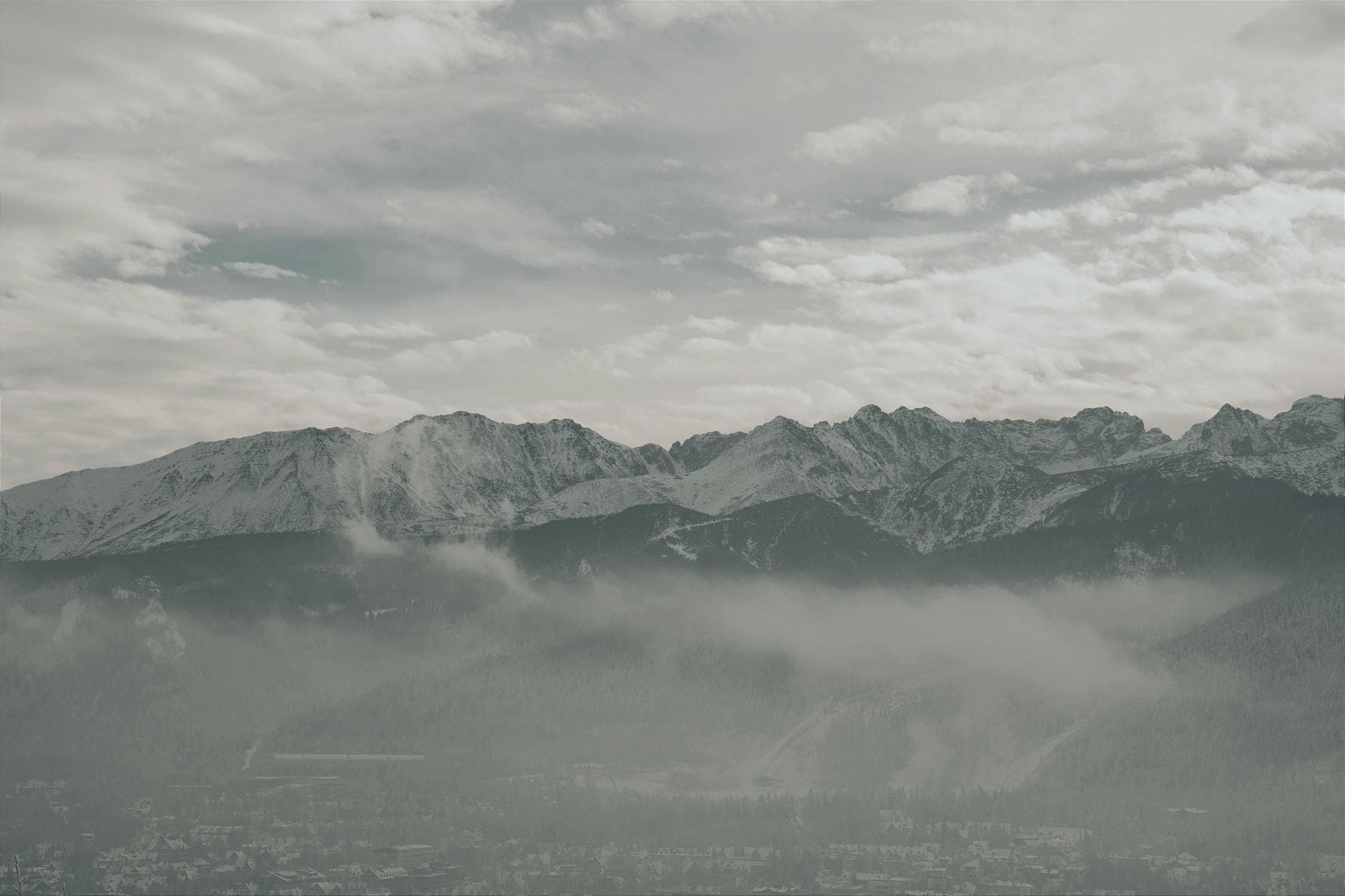 Captivating view of the snow-covered Tatra Mountains amidst clouds in Zakopane, Poland.