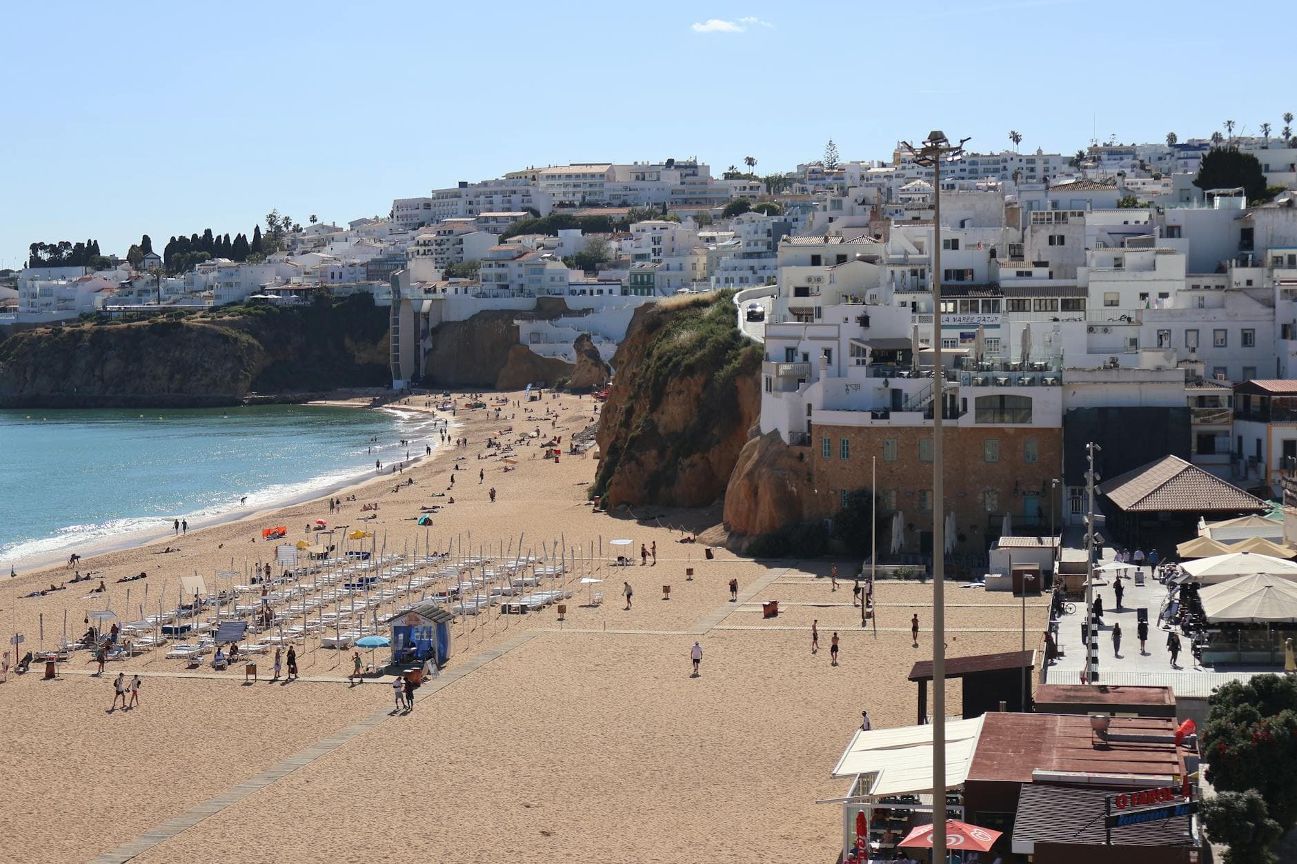 Charming beachfront scene with cascading white-washed buildings and golden sands in Albufeira, Portugal.