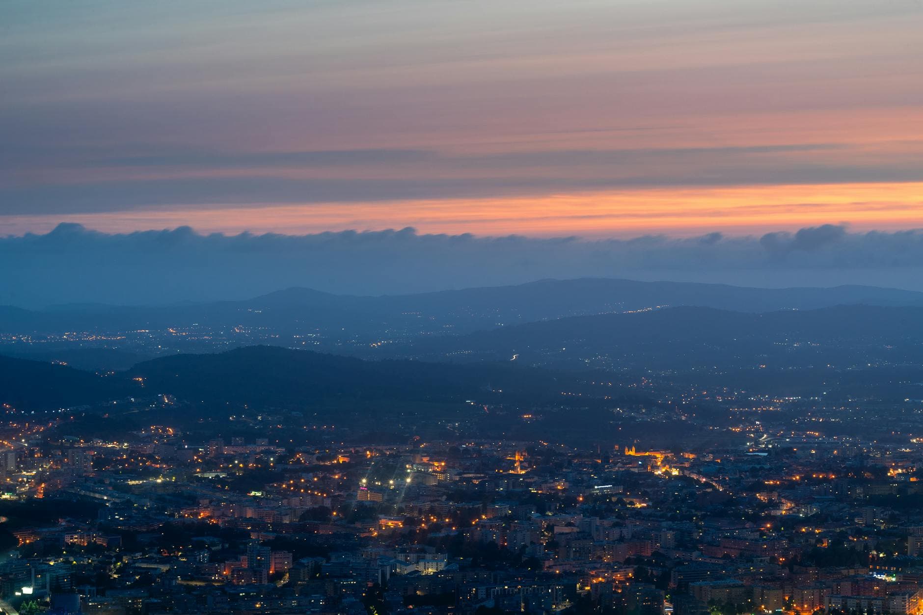 Stunning aerial view of Braga, Portugal, with city lights and colorful twilight sky.