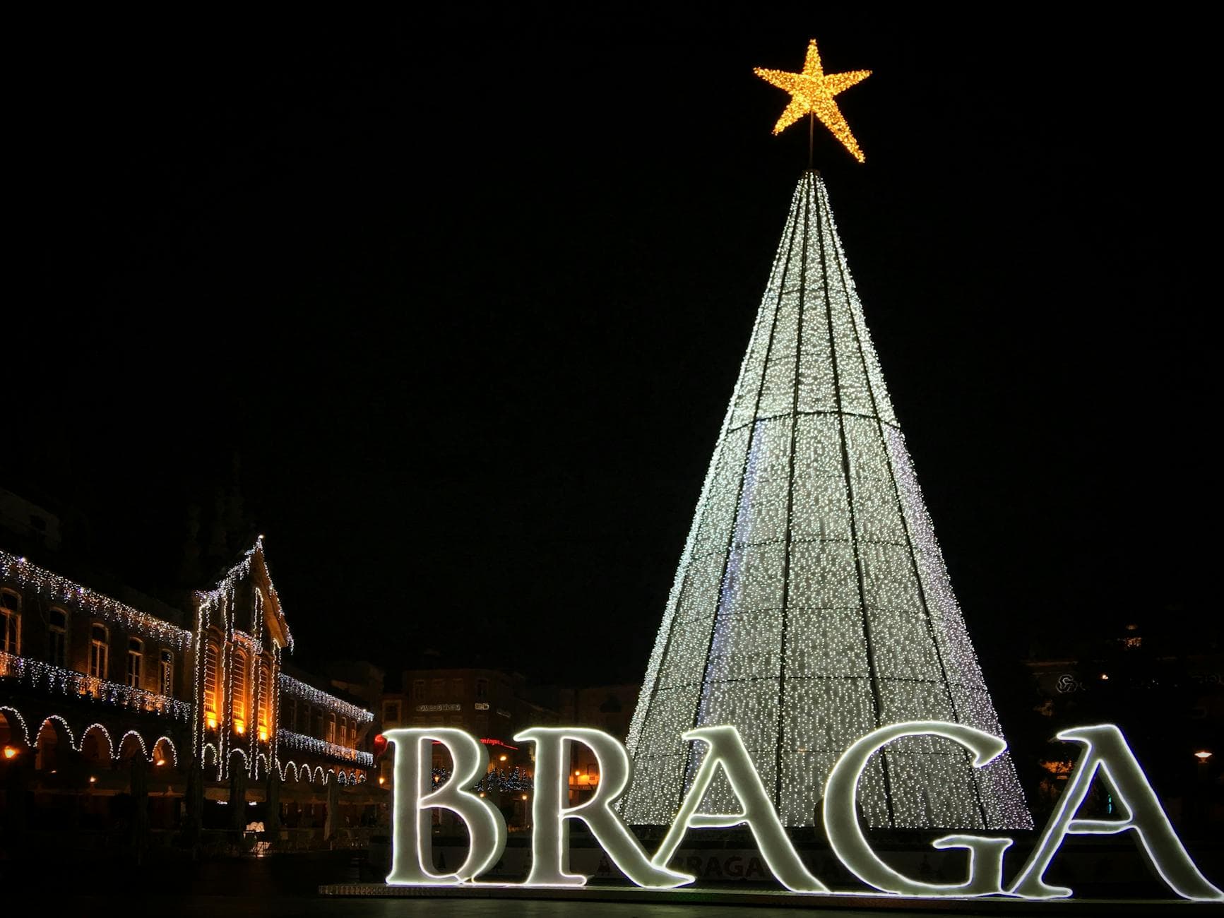 Illuminated giant Christmas tree and Braga sign in Portugal at night.