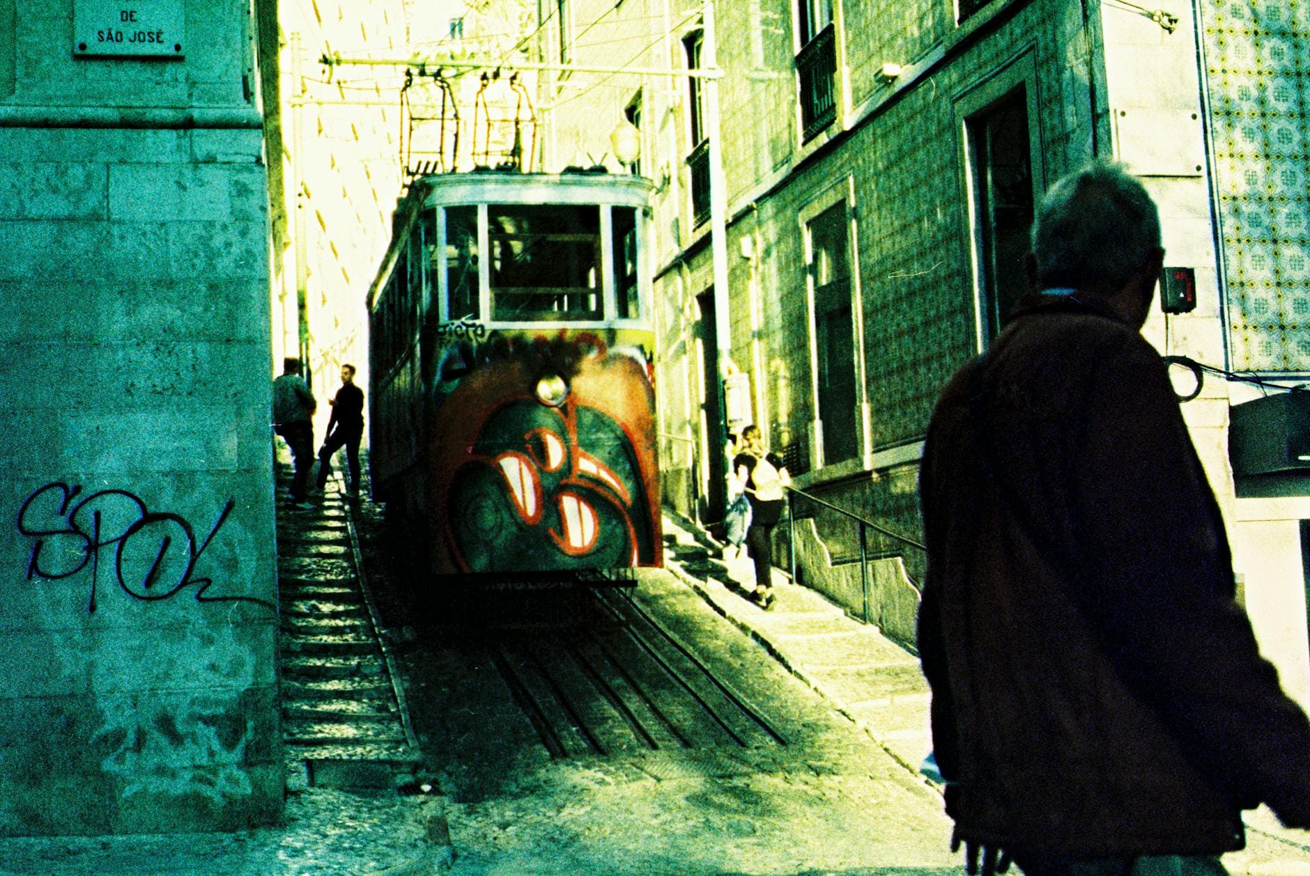Colorful Lisbon tram making its way through a narrow, bustling street against the backdrop of historic buildings.