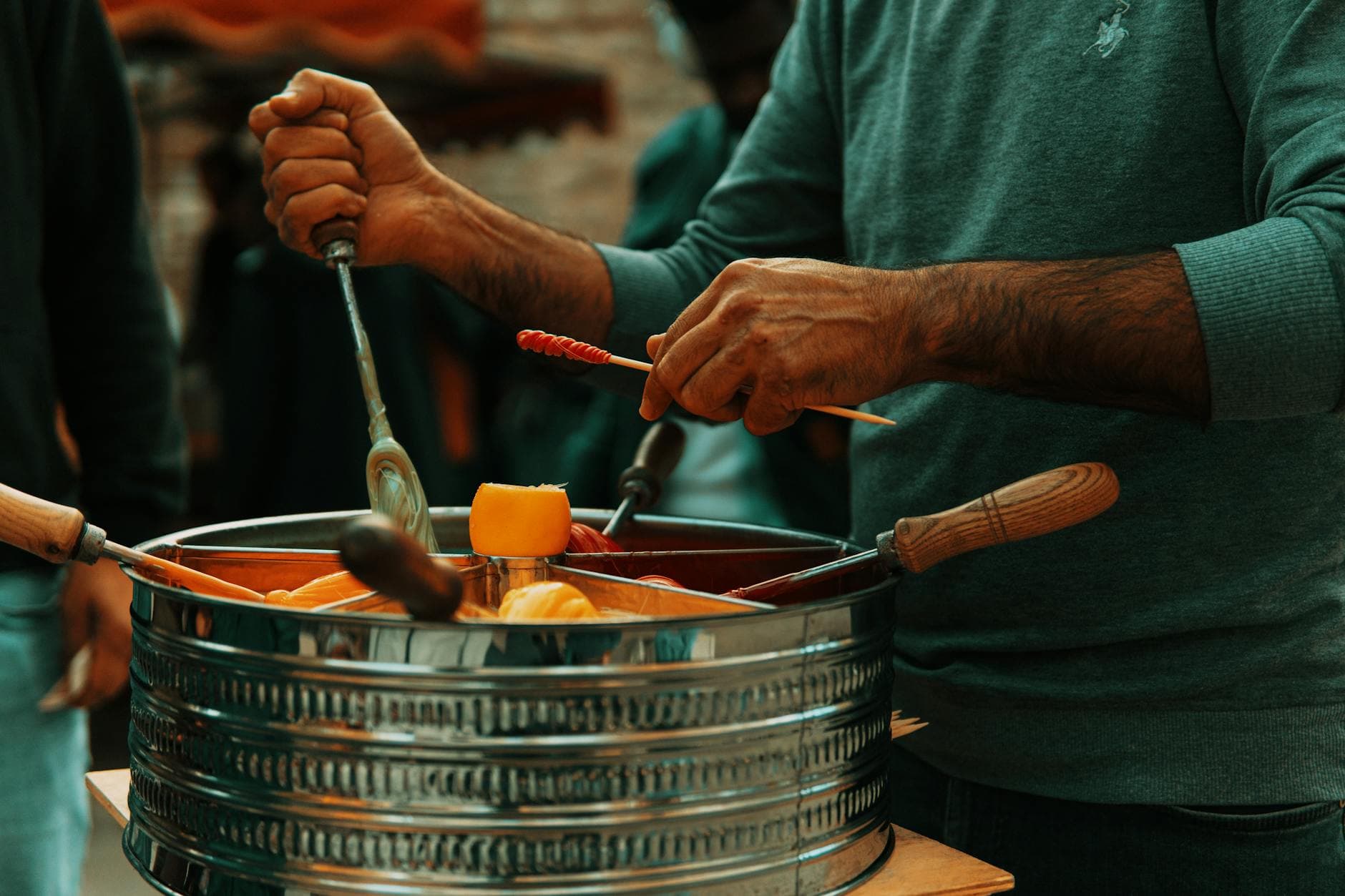 A man prepares traditional snacks using a large metal pot at a street market.