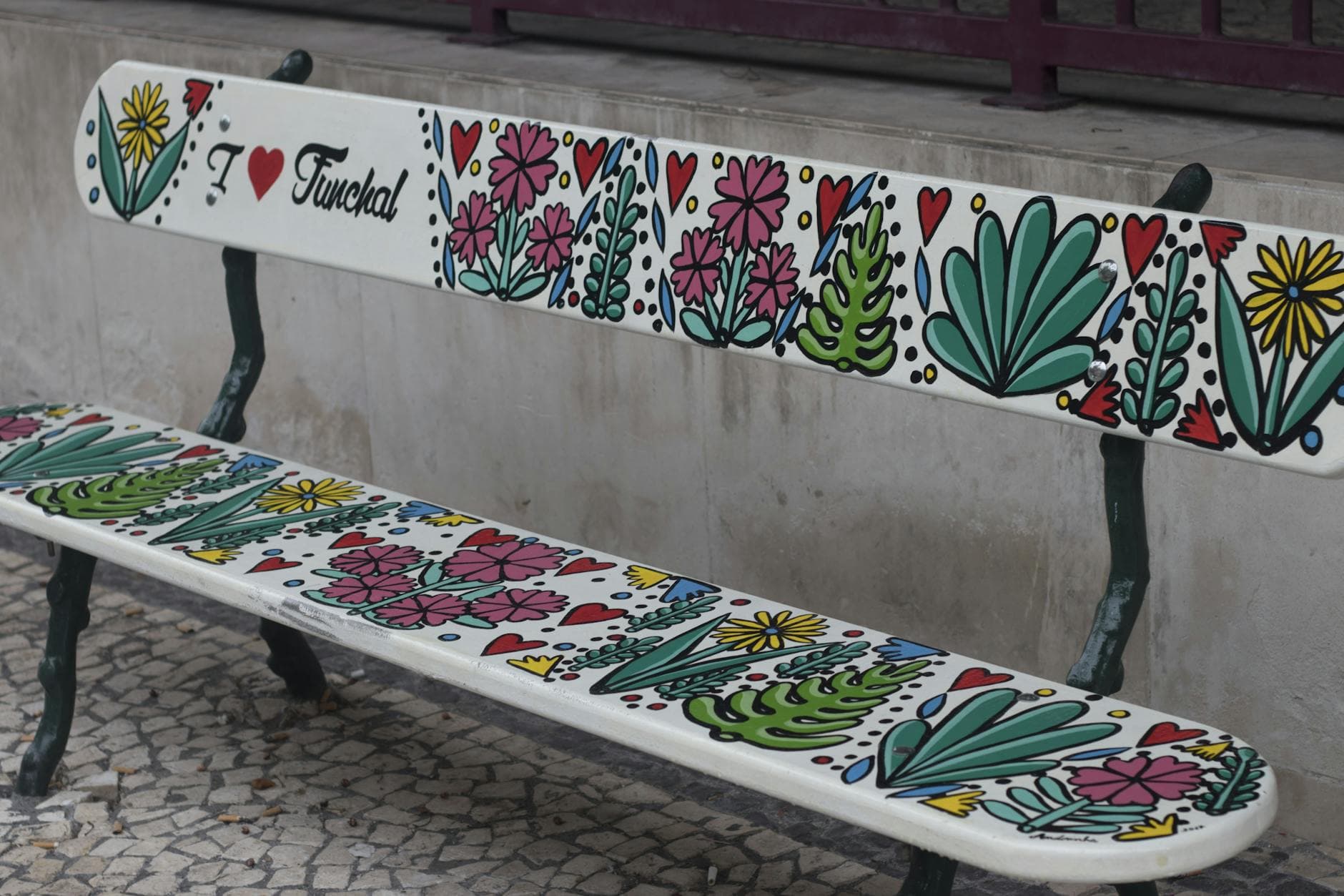 Vibrant decorated bench in Funchal, Madeira with floral designs and 'I Love Funchal' text.